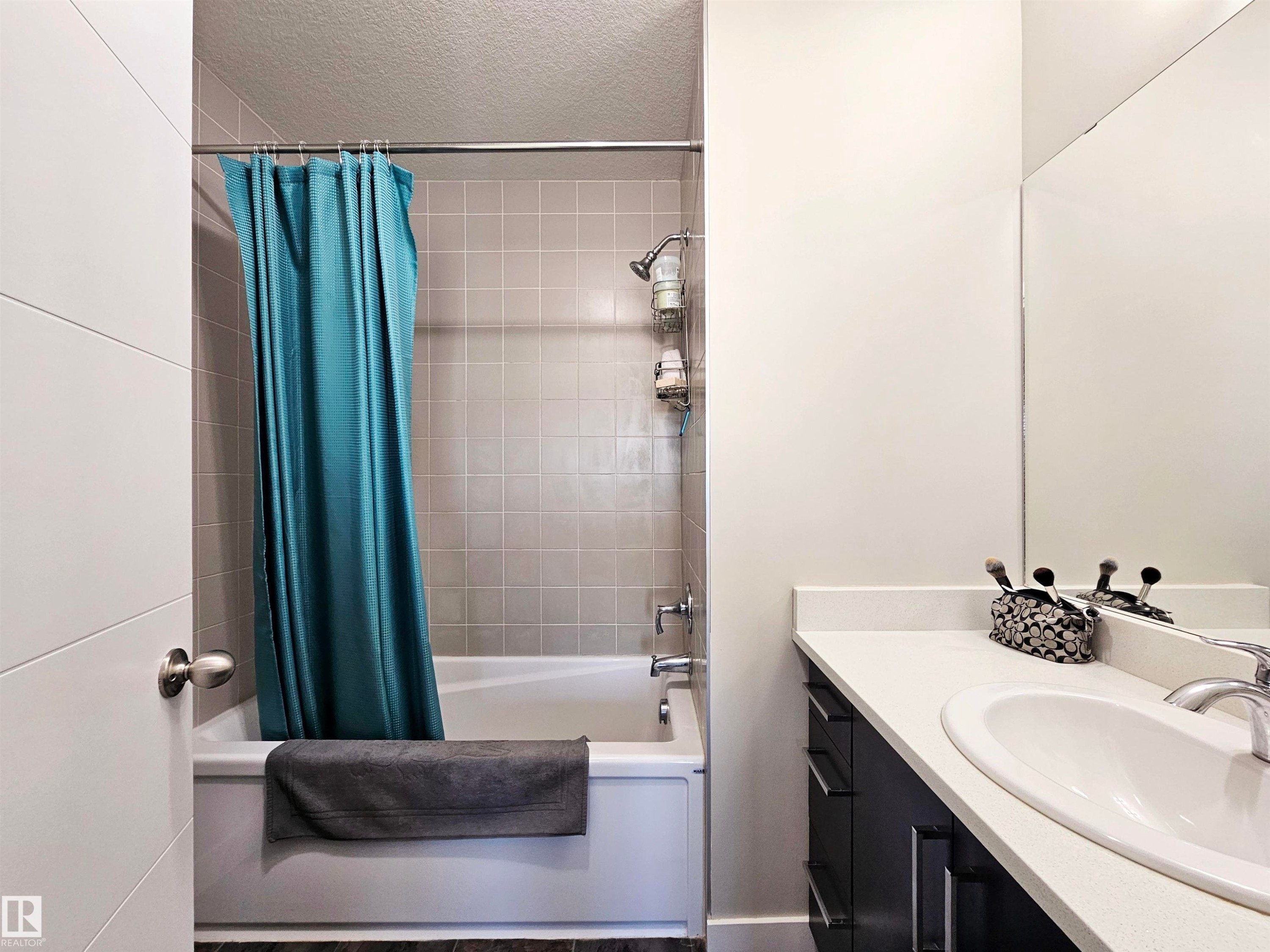 Bathroom with shower / bathtub combination with curtain, a textured ceiling, and vanity - 83 600 Bellerose Drive, St. Albert, AB - Indoor Photo Showing Bathroom