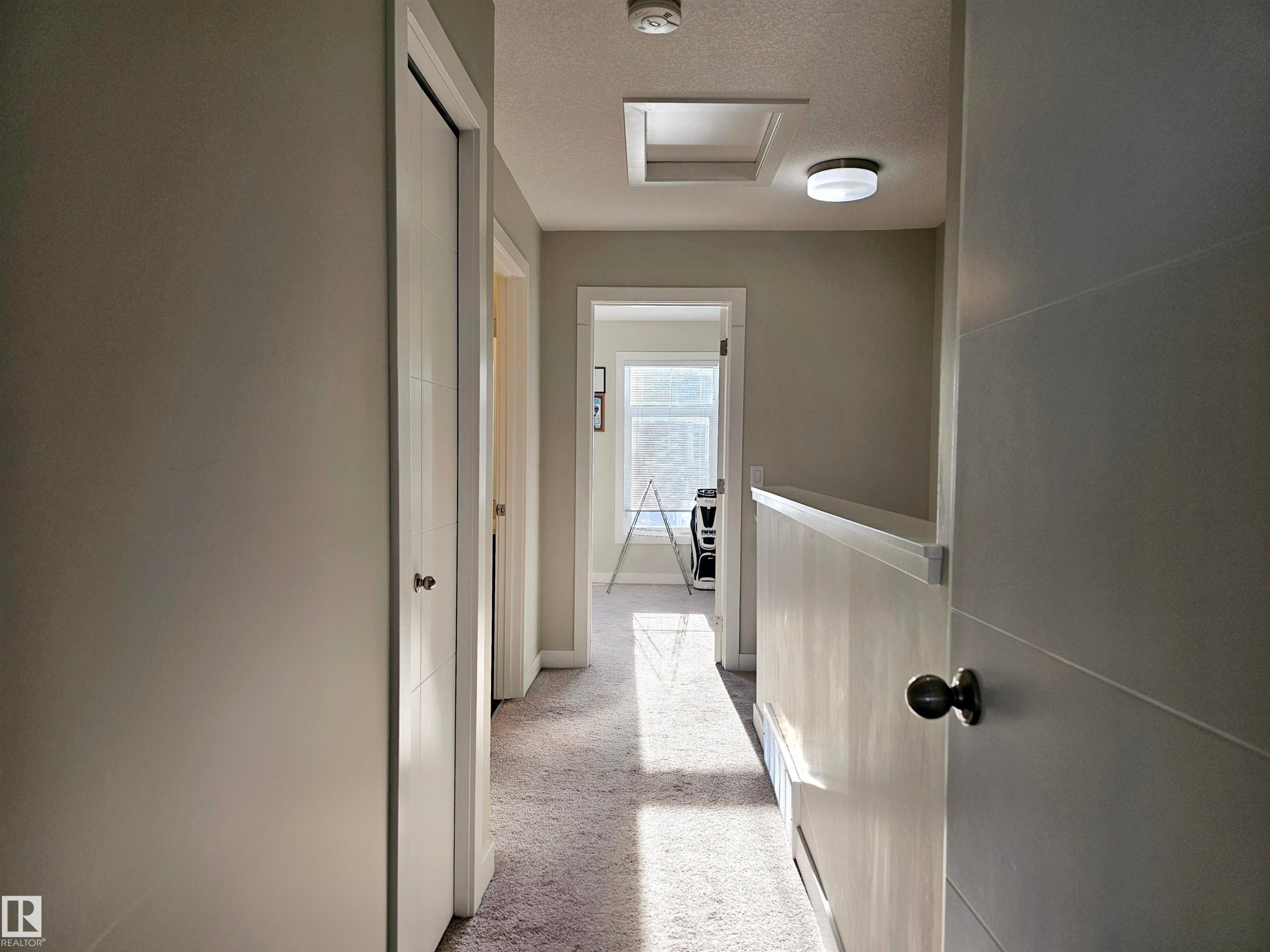 Hall with light colored carpet, a textured ceiling, and attic access - 83 600 Bellerose Drive, St. Albert, AB - Indoor Photo Showing Other Room