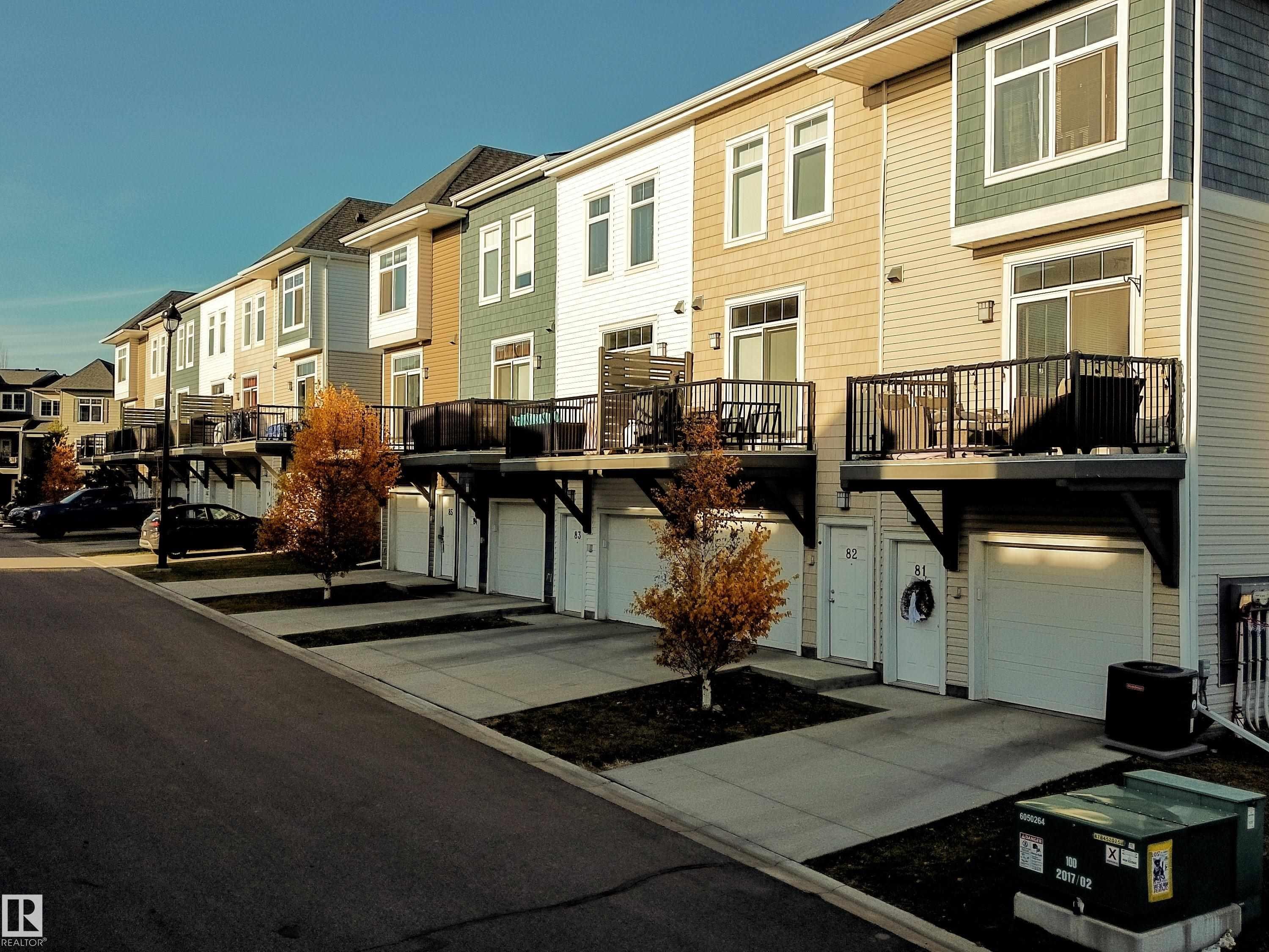 View of building exterior with a residential view, driveway, and a garage - 83 600 Bellerose Drive, St. Albert, AB - Outdoor