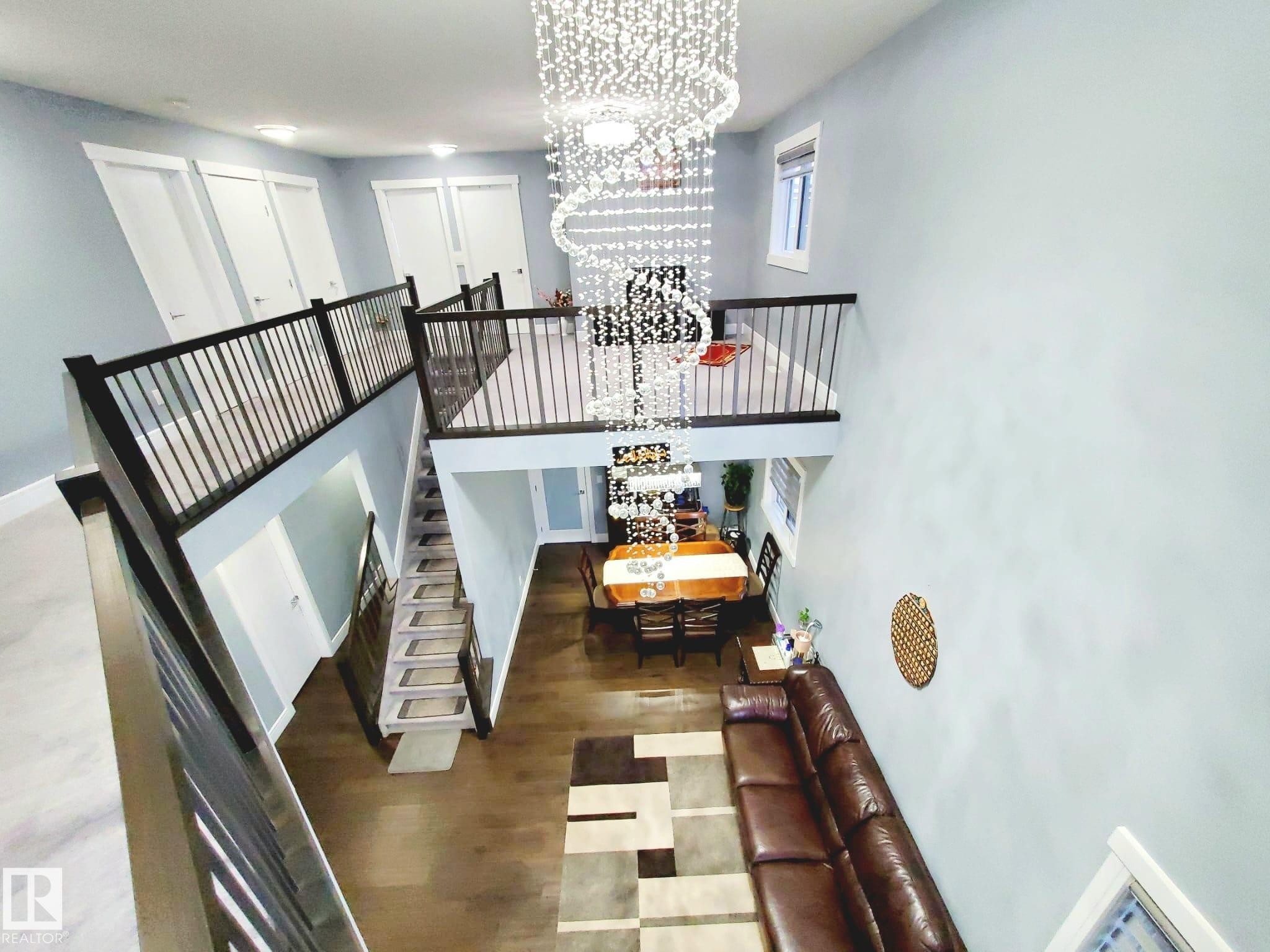 Staircase with a chandelier, wood finished floors, and a high ceiling - 1357 Watt Drive, Edmonton, AB - Indoor Photo Showing Other Room