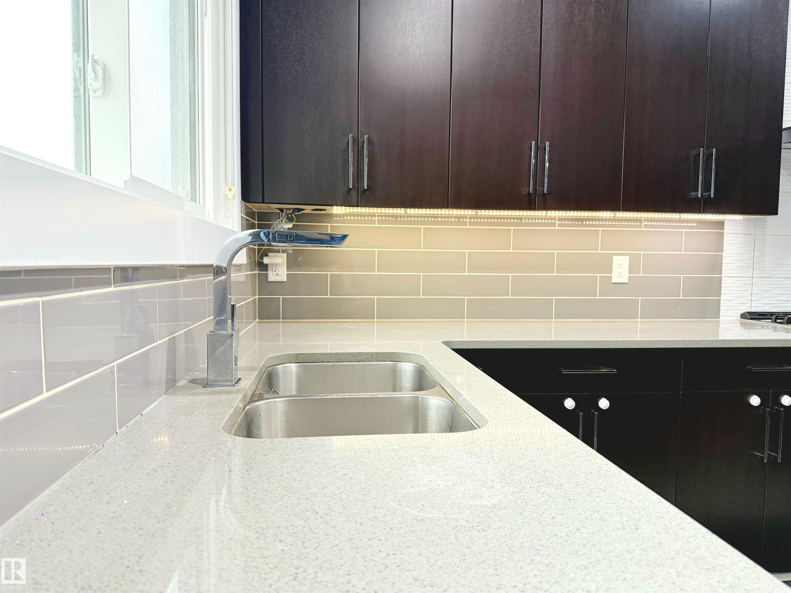 Kitchen featuring tasteful backsplash, light stone counters, modern cabinets, and dark brown cabinets - 1357 Watt Drive, Edmonton, AB - Indoor Photo Showing Kitchen With Double Sink