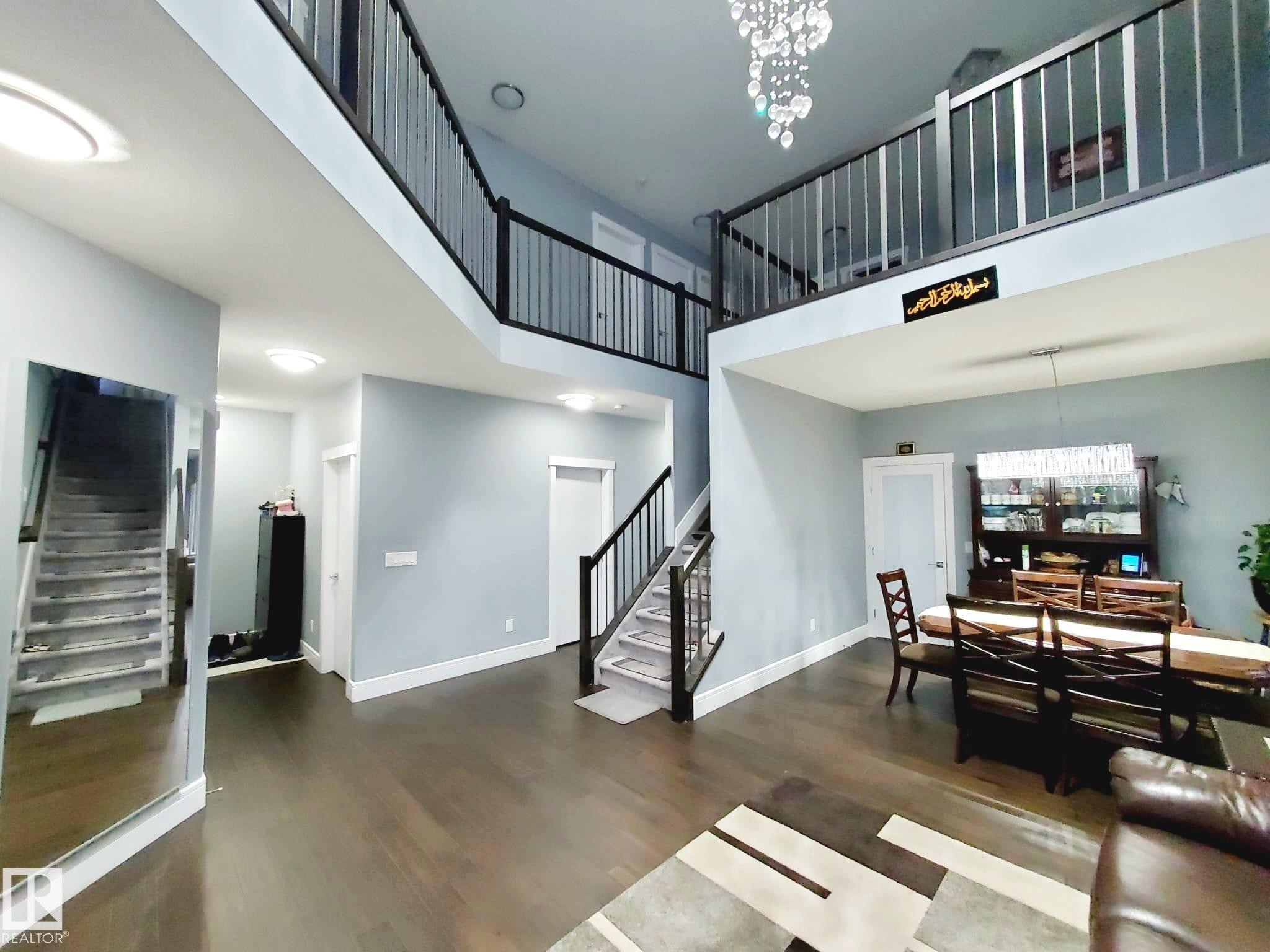 Living area featuring stairs, a chandelier, a towering ceiling, and dark wood-type flooring - 1357 Watt Drive, Edmonton, AB - Indoor