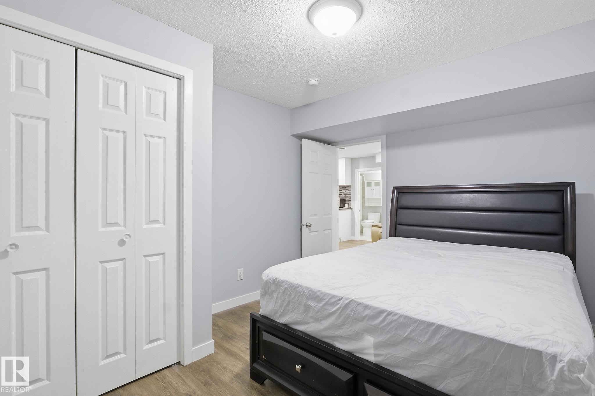 Bedroom with light wood finished floors, a closet, and a textured ceiling - 893 Ebbers Crescent Nw, Edmonton, AB - Indoor Photo Showing Bedroom