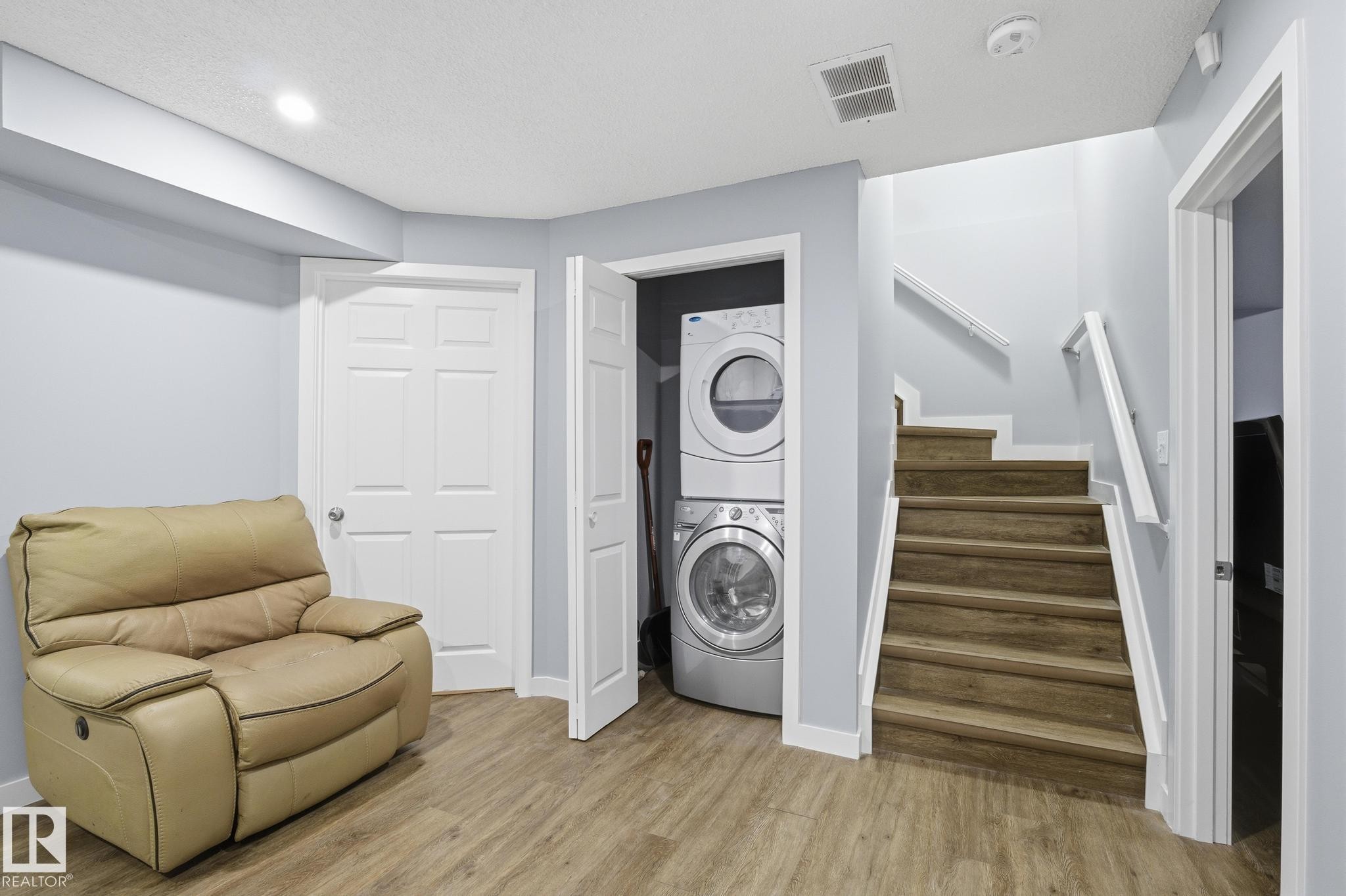 Laundry room with light wood-style flooring, estacked washer and dryer, and recessed lighting - 893 Ebbers Crescent Nw, Edmonton, AB - Indoor Photo Showing Laundry Room