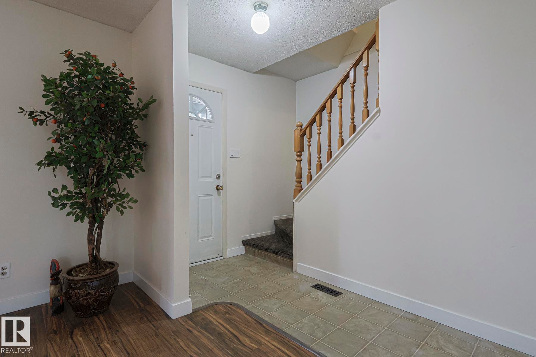 Foyer entrance with a textured ceiling, stairway, and light tile patterned floors - 51 Belmead Gardens, Edmonton, AB - Indoor Photo Showing Other Room
