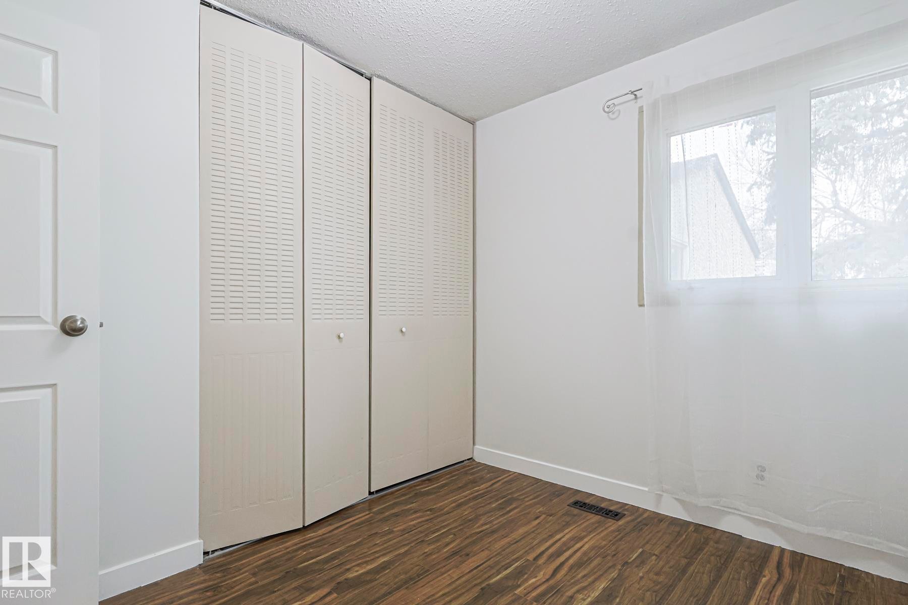 Unfurnished bedroom with a textured ceiling, dark wood-style flooring, and a closet - 51 Belmead Gardens, Edmonton, AB - Indoor Photo Showing Other Room