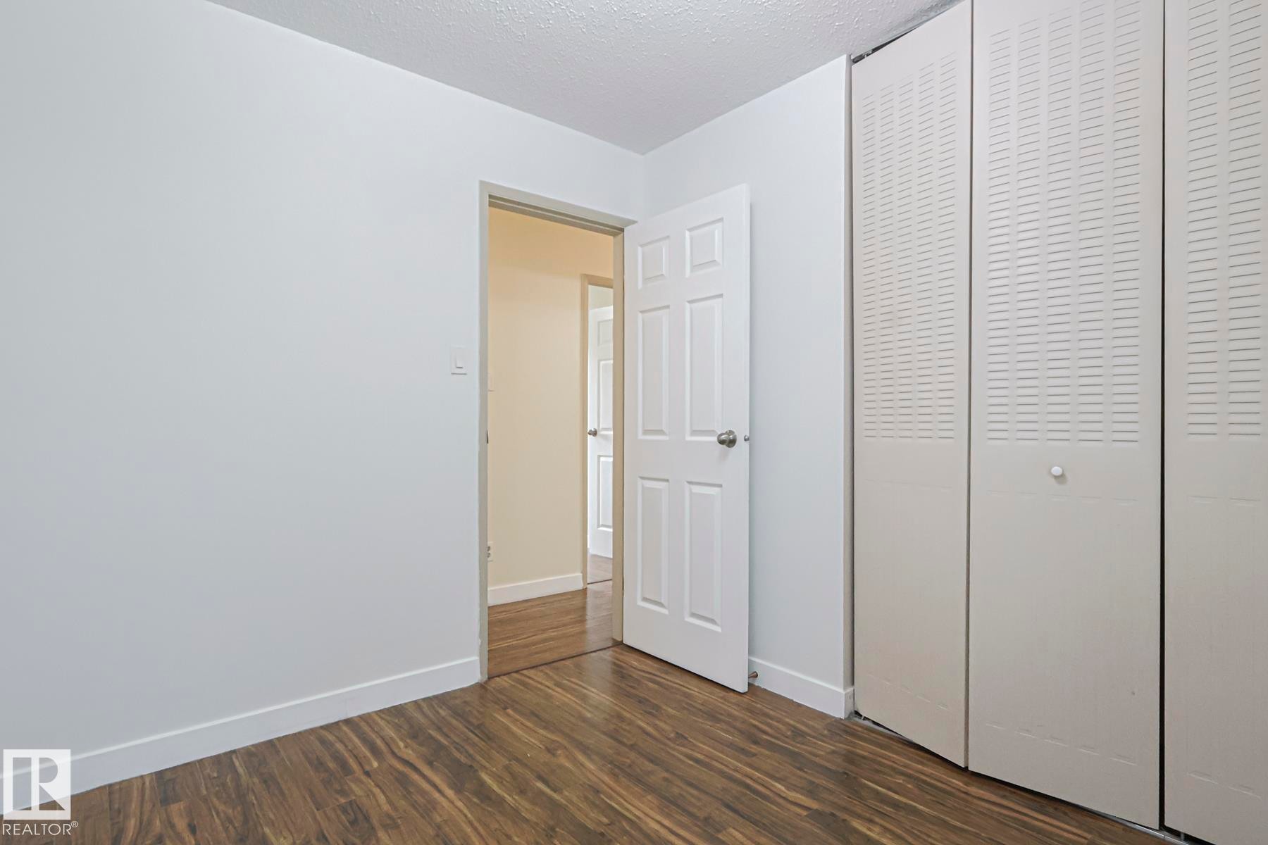 Unfurnished bedroom with dark wood-style flooring, a textured ceiling, and a closet - 51 Belmead Gardens, Edmonton, AB - Indoor Photo Showing Other Room
