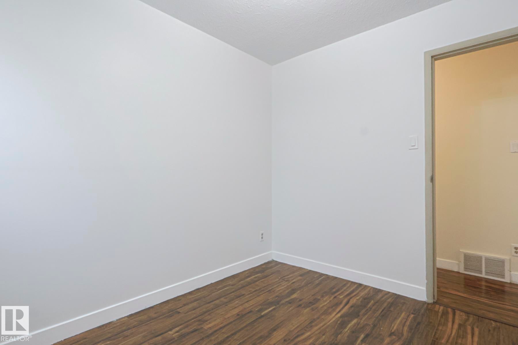 Empty room with dark wood-style floors and a textured ceiling - 51 Belmead Gardens, Edmonton, AB - Indoor Photo Showing Other Room