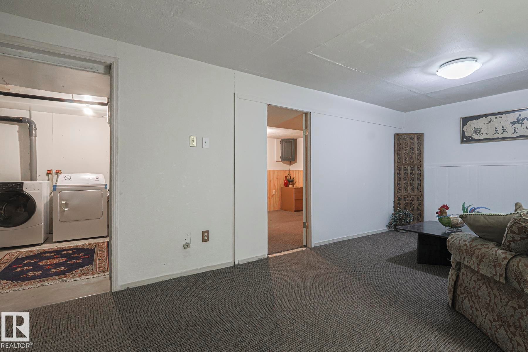 Carpeted living room featuring washing machine and clothes dryer and baseboards - 51 Belmead Gardens, Edmonton, AB - Indoor Photo Showing Laundry Room
