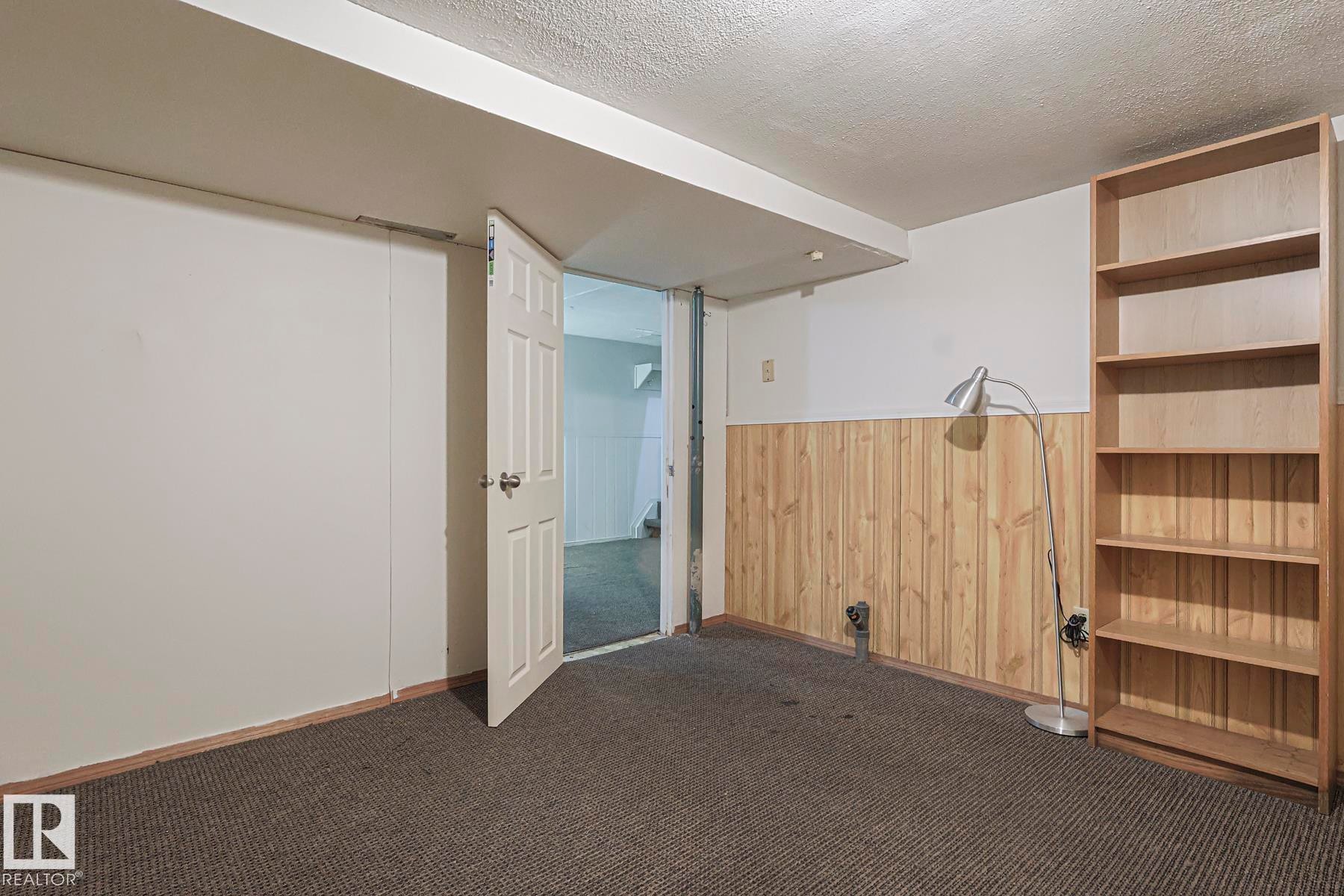 Spare room with wood walls, dark colored carpet, wainscoting, and a textured ceiling - 51 Belmead Gardens, Edmonton, AB - Indoor Photo Showing Other Room