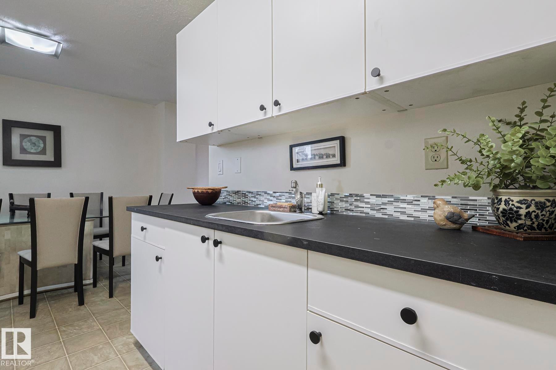 Kitchen featuring dark countertops, white cabinetry, decorative backsplash, and light tile patterned floors - 51 Belmead Gardens, Edmonton, AB - Indoor Photo Showing Kitchen