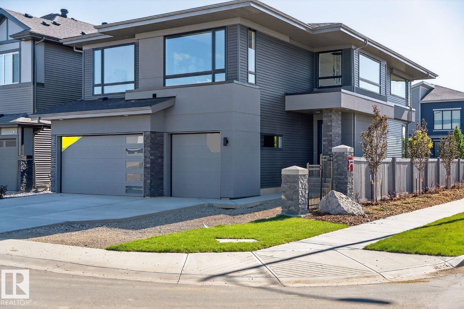 View of front facade featuring stucco siding, stone siding, an attached garage, concrete driveway, and a balcony - 6703 Knox Crest, Edmonton, AB - Outdoor