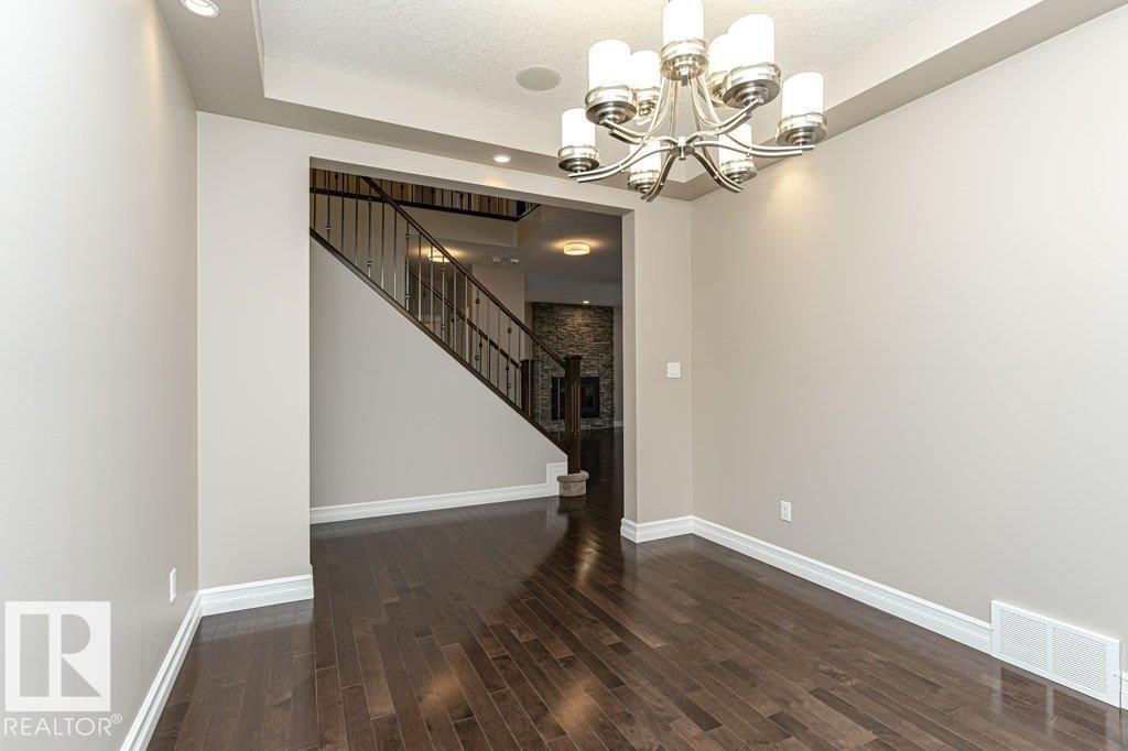 Unfurnished dining area with a chandelier, dark wood-style floors, a textured ceiling, stairway, and recessed lighting - 3198 Winspear Crescent Sw, Edmonton, AB - Indoor Photo Showing Other Room