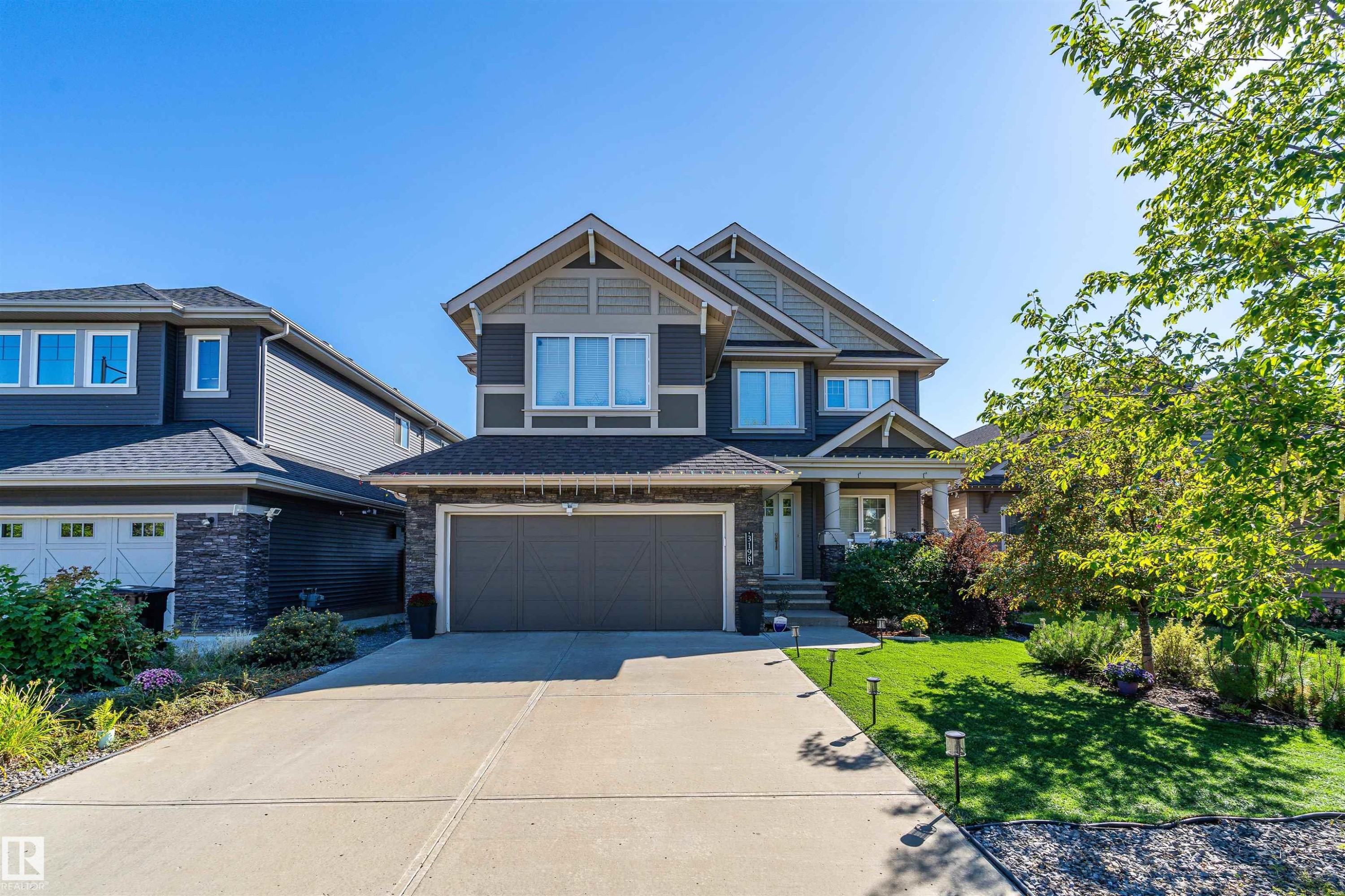 Craftsman inspired home featuring concrete driveway, a front yard, stone siding, an attached garage, and roof with shingles - 3198 Winspear Crescent Sw, Edmonton, AB - Outdoor With Facade