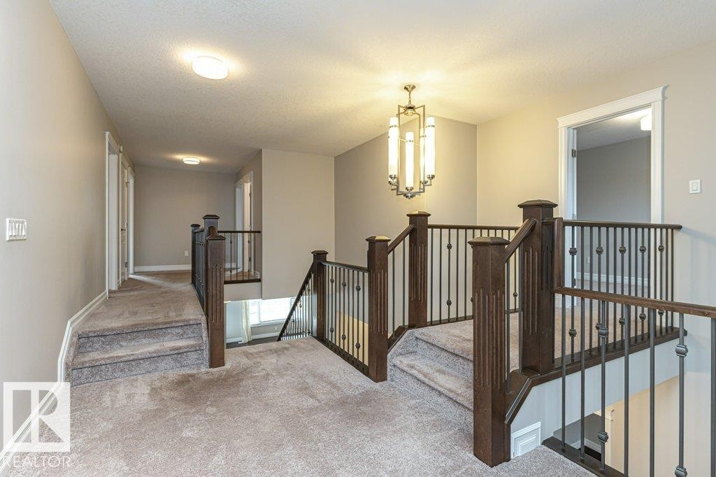 Stairway featuring a chandelier, carpet, and a textured ceiling - 3198 Winspear Crescent Sw, Edmonton, AB - Indoor Photo Showing Other Room
