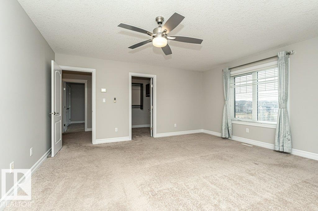 Unfurnished bedroom featuring a spacious closet, a textured ceiling, light colored carpet, and a ceiling fan - 3198 Winspear Crescent Sw, Edmonton, AB - Indoor Photo Showing Other Room