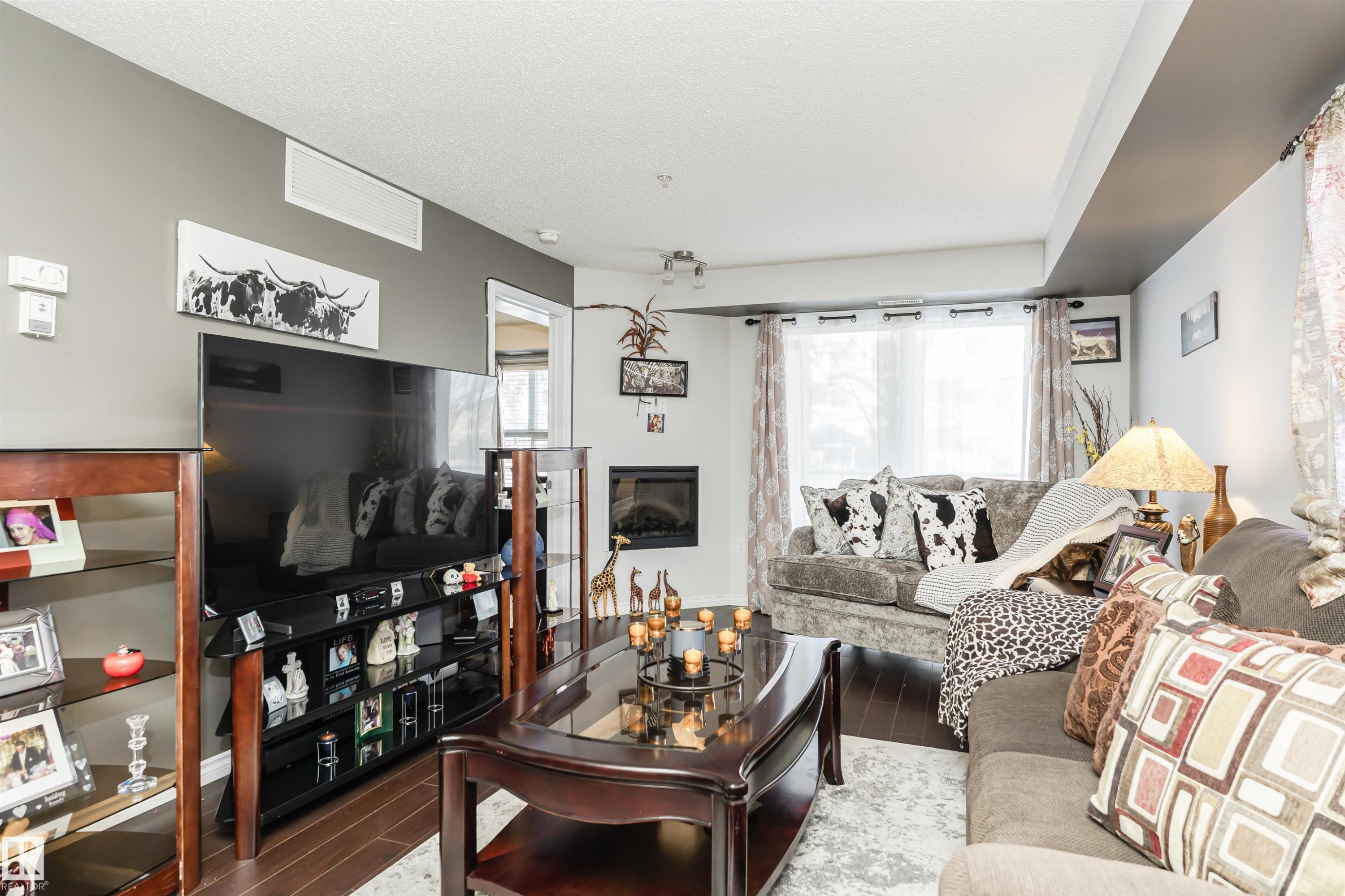 Living room with wood finished floors and a textured ceiling - 107 10118 106 Avenue, Edmonton, AB - Indoor Photo Showing Living Room With Fireplace