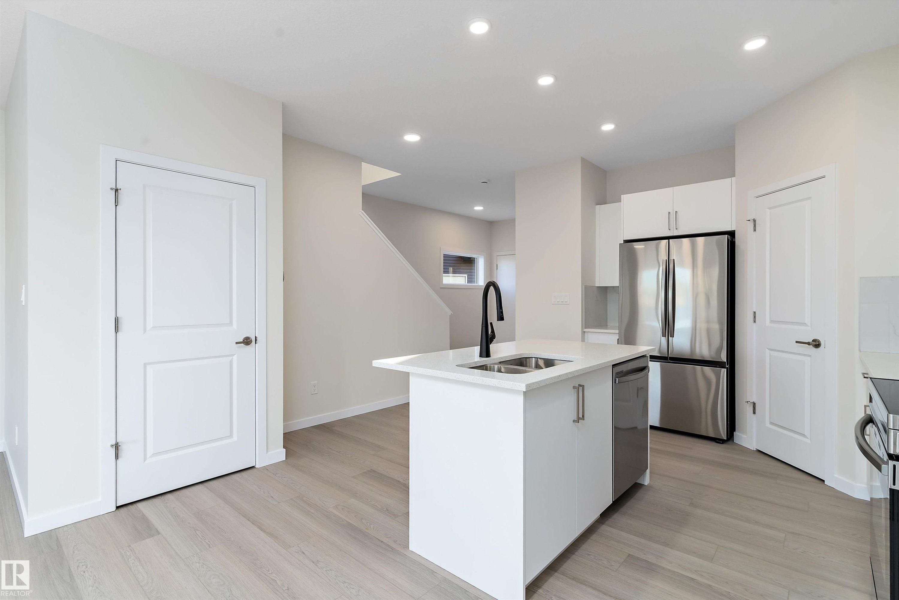 Kitchen with an island with sink, stainless steel appliances, white cabinetry, light wood-type flooring, and recessed lighting - 823 Rowan Close, Edmonton, AB - Indoor Photo Showing Kitchen With Double Sink With Upgraded Kitchen