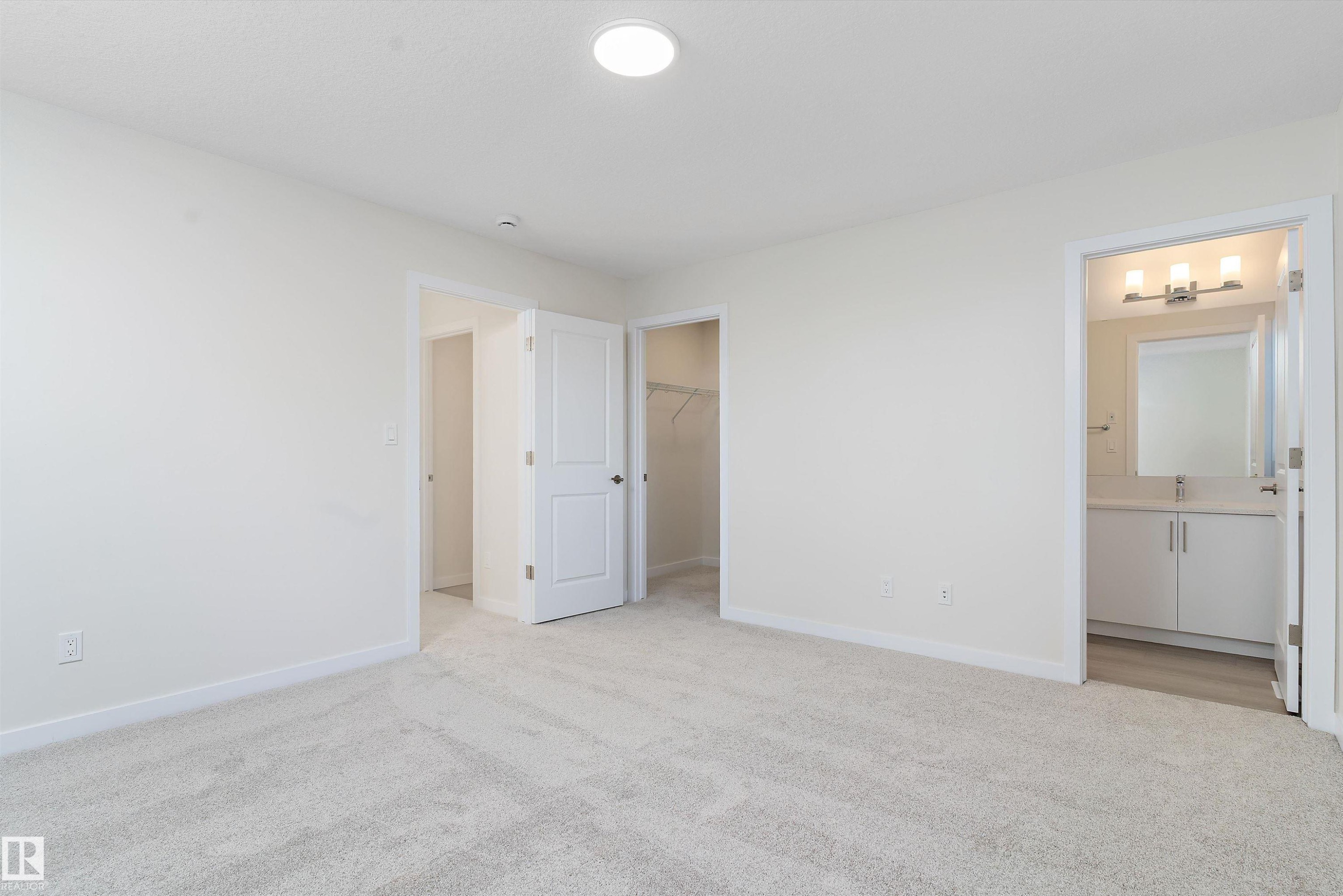 Unfurnished bedroom featuring a walk in closet, light carpet, and ensuite bath - 823 Rowan Close, Edmonton, AB - Indoor Photo Showing Other Room