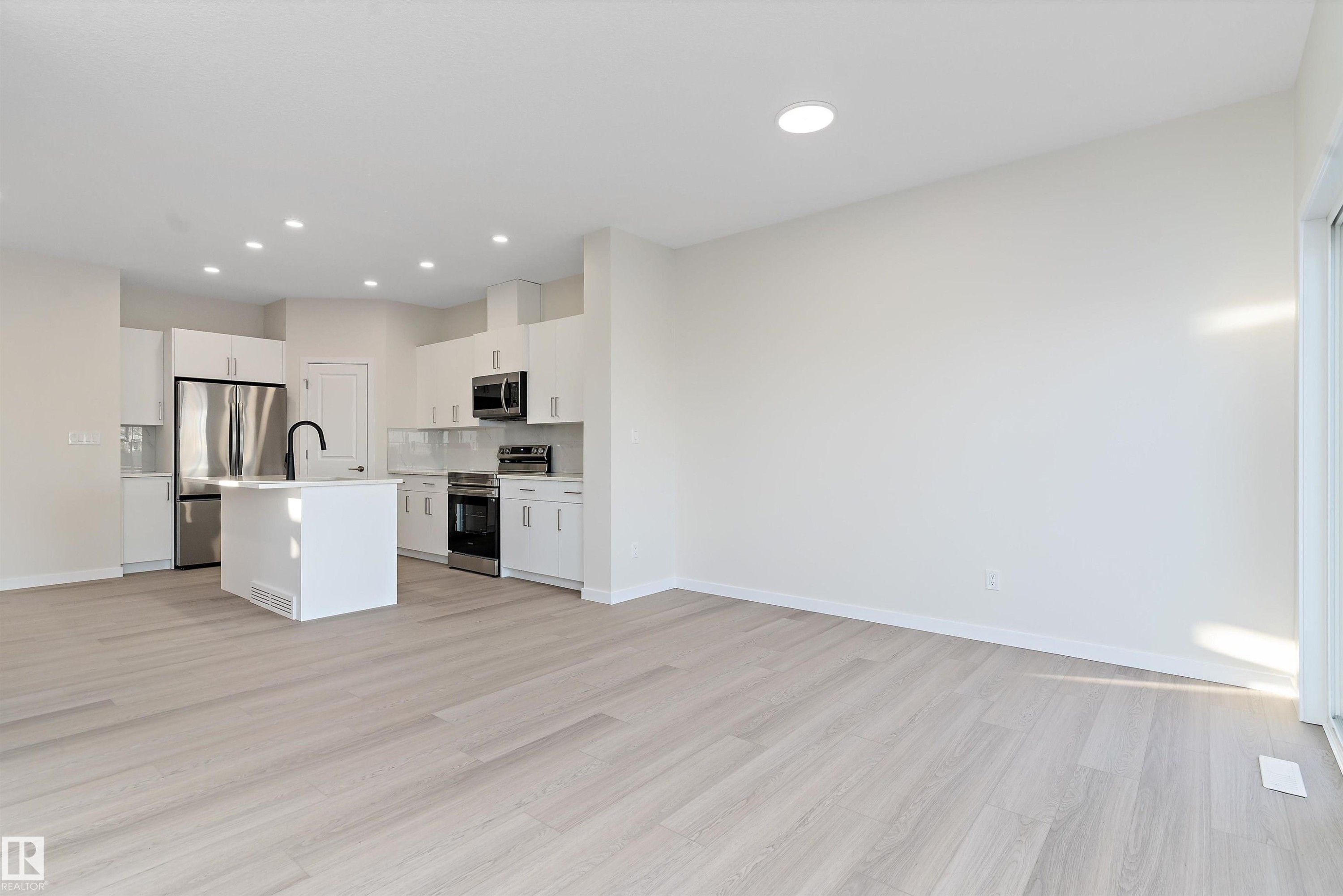 Kitchen with light countertops, white cabinetry, a kitchen island with sink, open floor plan, and recessed lighting - 823 Rowan Close, Edmonton, AB - Indoor Photo Showing Kitchen With Upgraded Kitchen