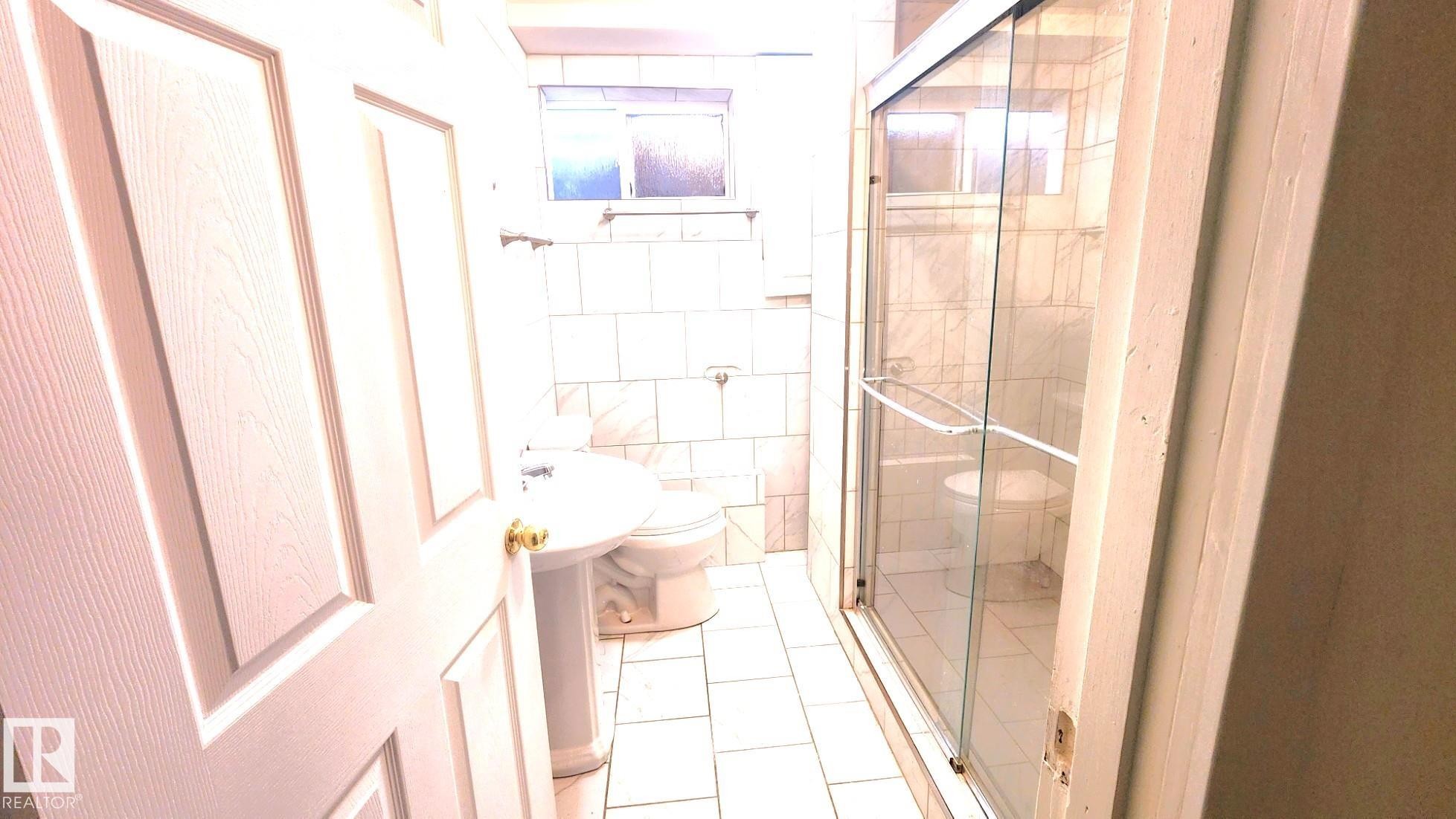 Bathroom with tile walls, a stall shower, and light tile patterned floors - 11516 133A Avenue, Edmonton, AB - Indoor Photo Showing Bathroom