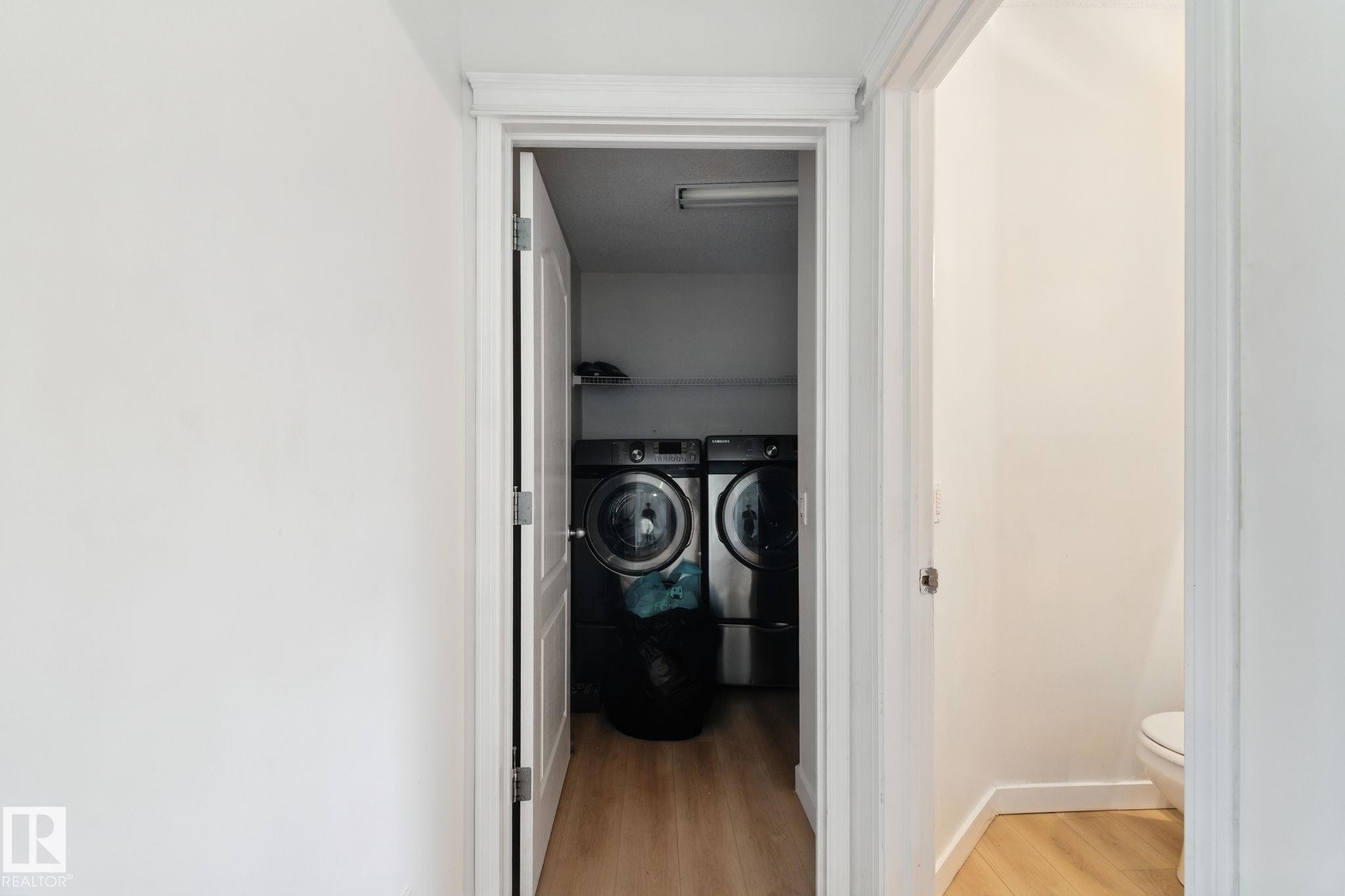 Corridor with light wood-style flooring and washing machine and dryer - 7836 7 Avenue, Edmonton, AB - Indoor