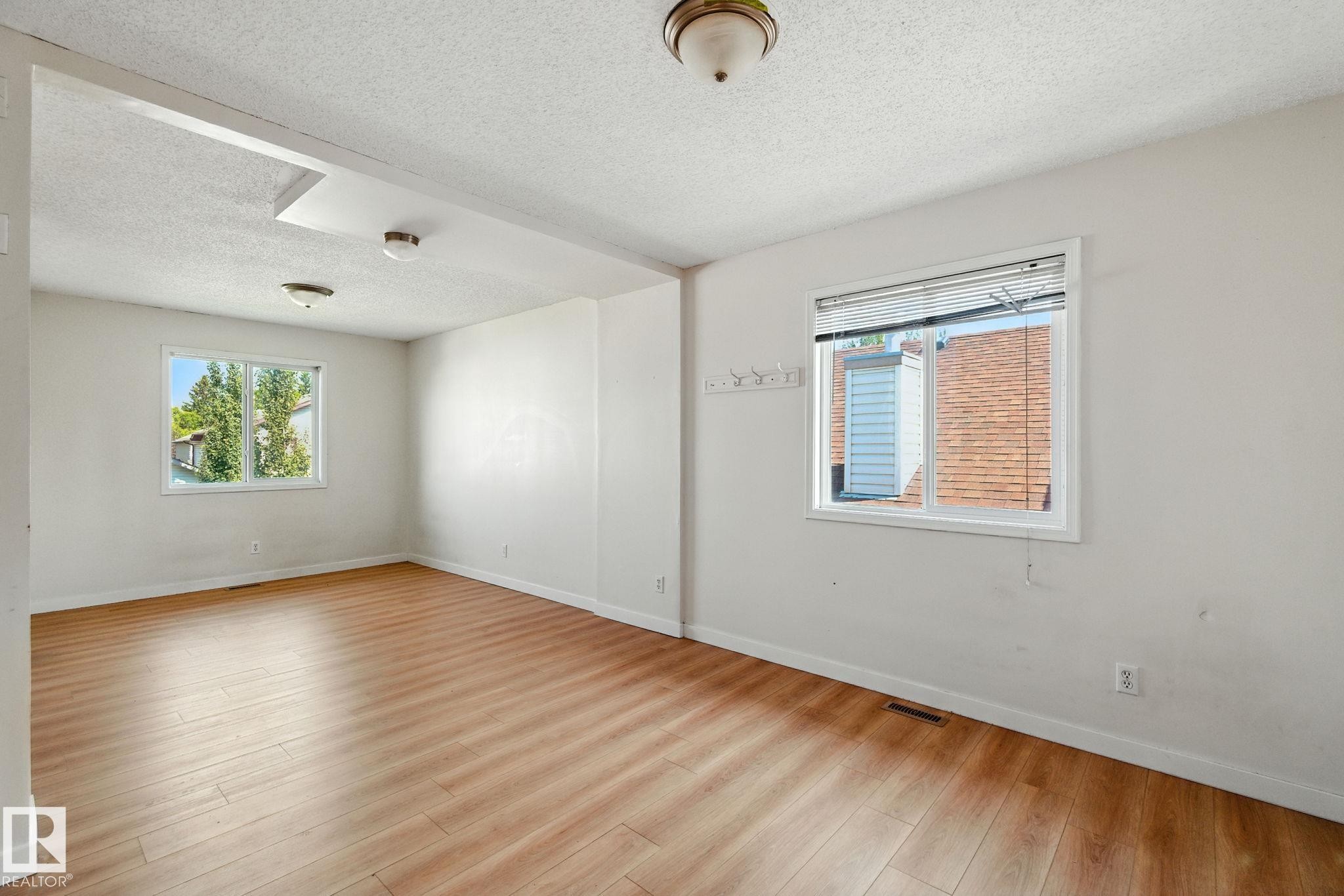 Empty room with a textured ceiling and light wood-style floors - 7836 7 Avenue, Edmonton, AB - Indoor Photo Showing Other Room