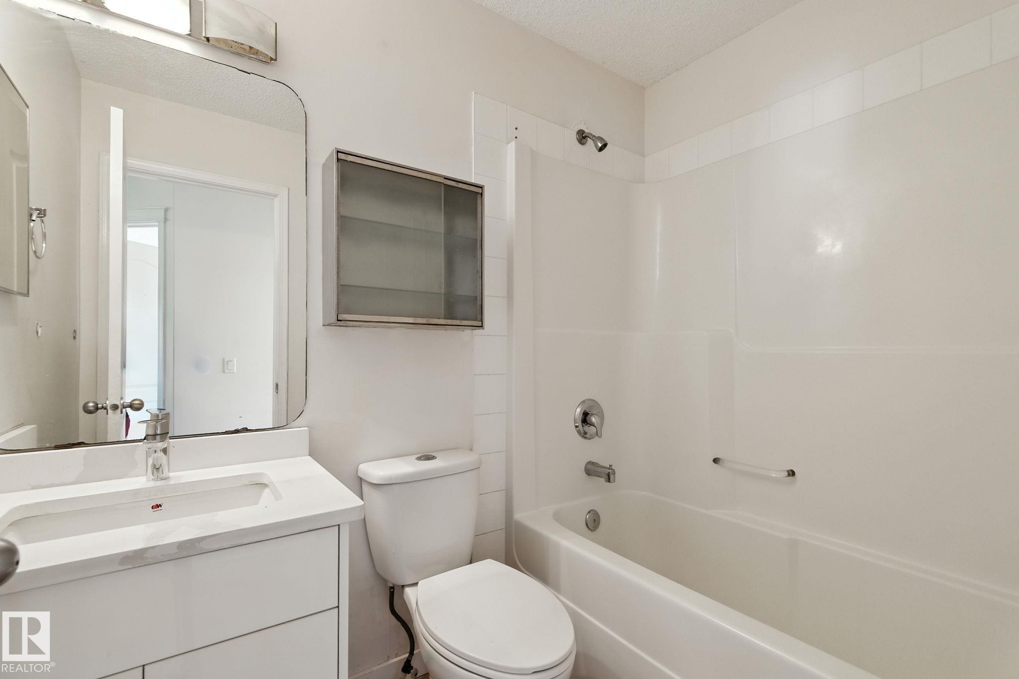 Full bathroom with vanity, washtub / shower combination, and a textured ceiling - 7836 7 Avenue, Edmonton, AB - Indoor Photo Showing Bathroom