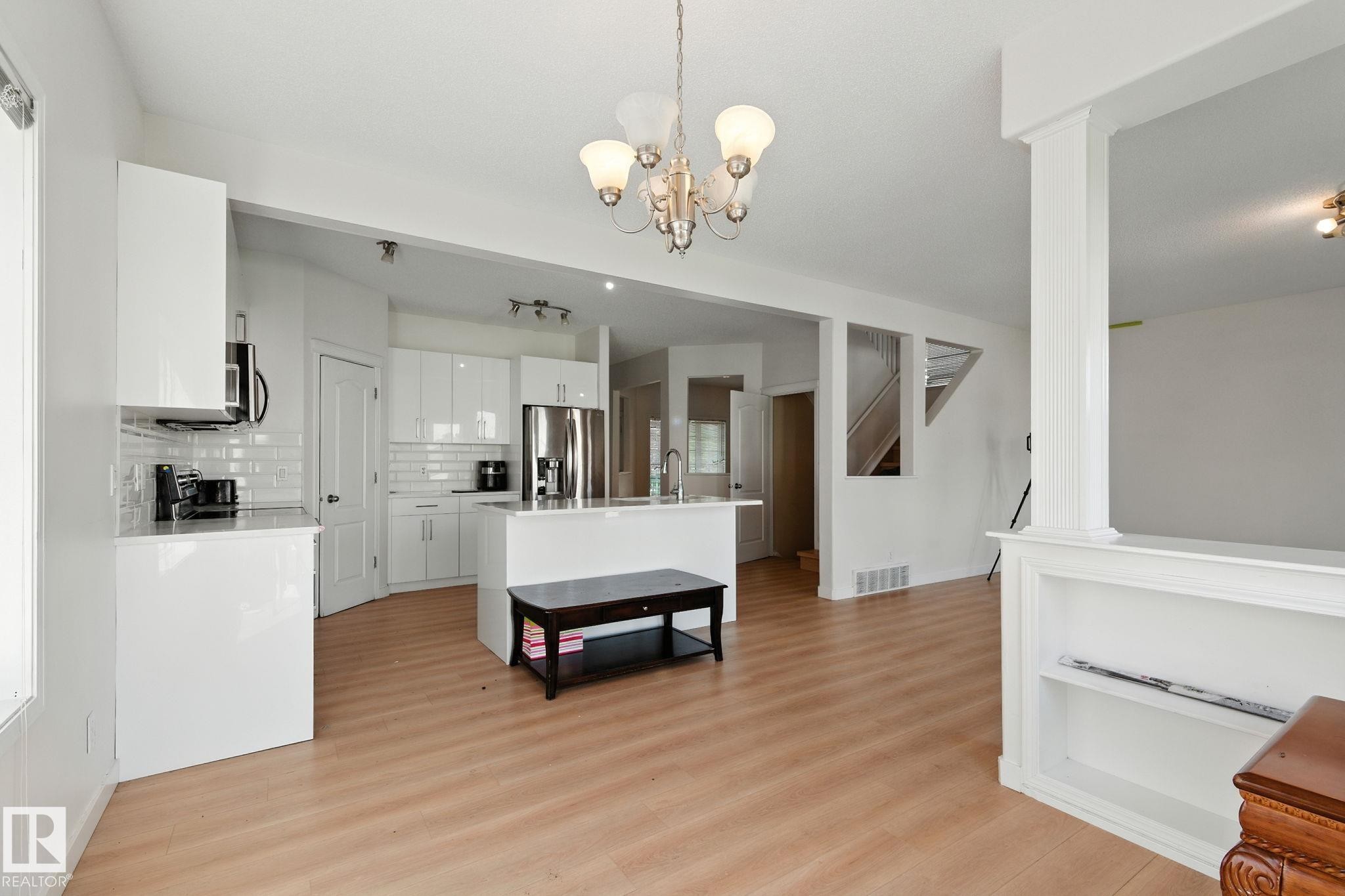 Dining space with light wood-style floors, track lighting, and a chandelier - 7836 7 Avenue, Edmonton, AB - Indoor Photo Showing Kitchen