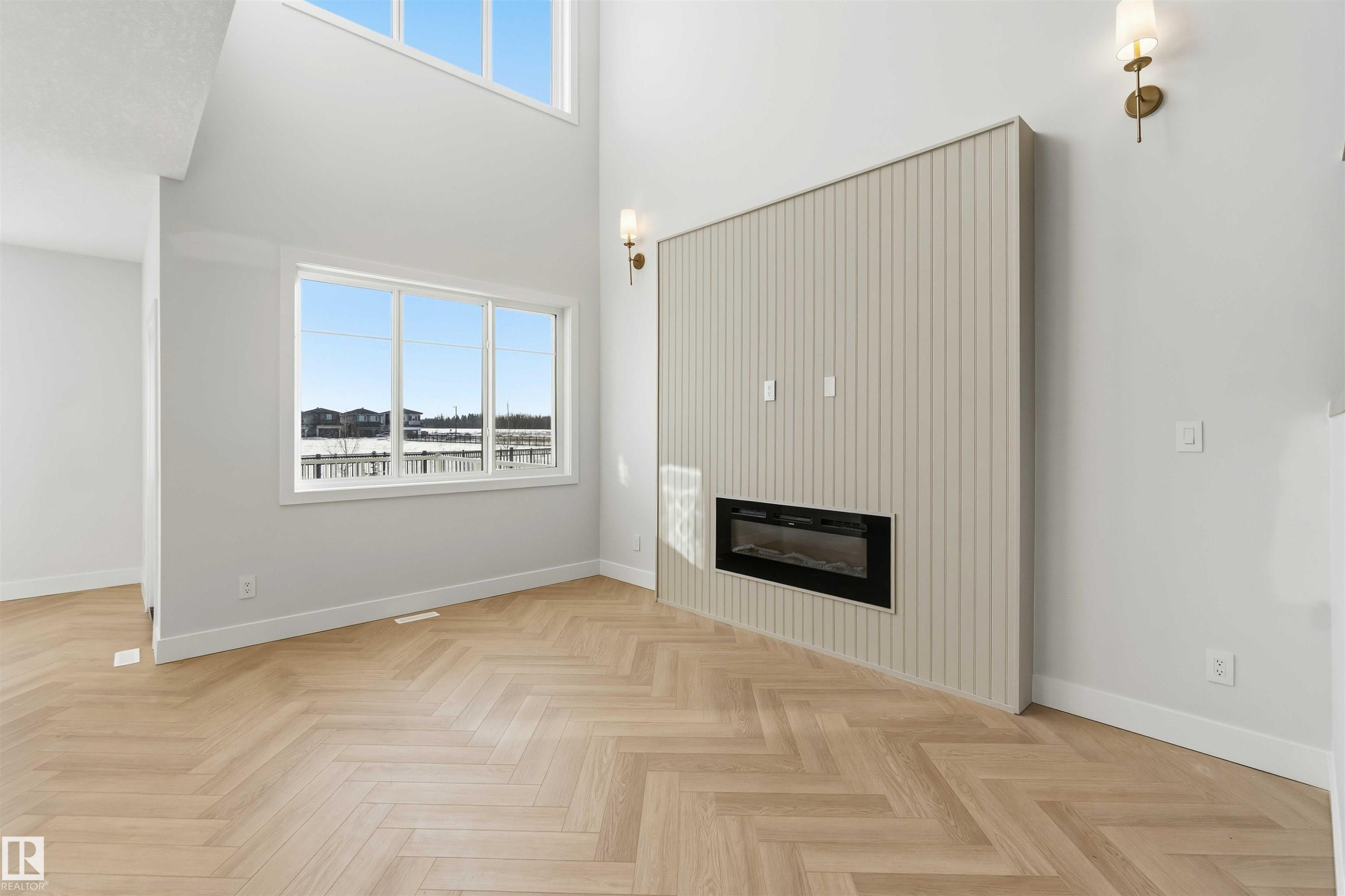 Unfurnished living room featuring a glass covered fireplace, a high ceiling, parquet floors, and healthy amount of natural light - 94 Eldridge Pointe, St. Albert, AB - Indoor With Fireplace
