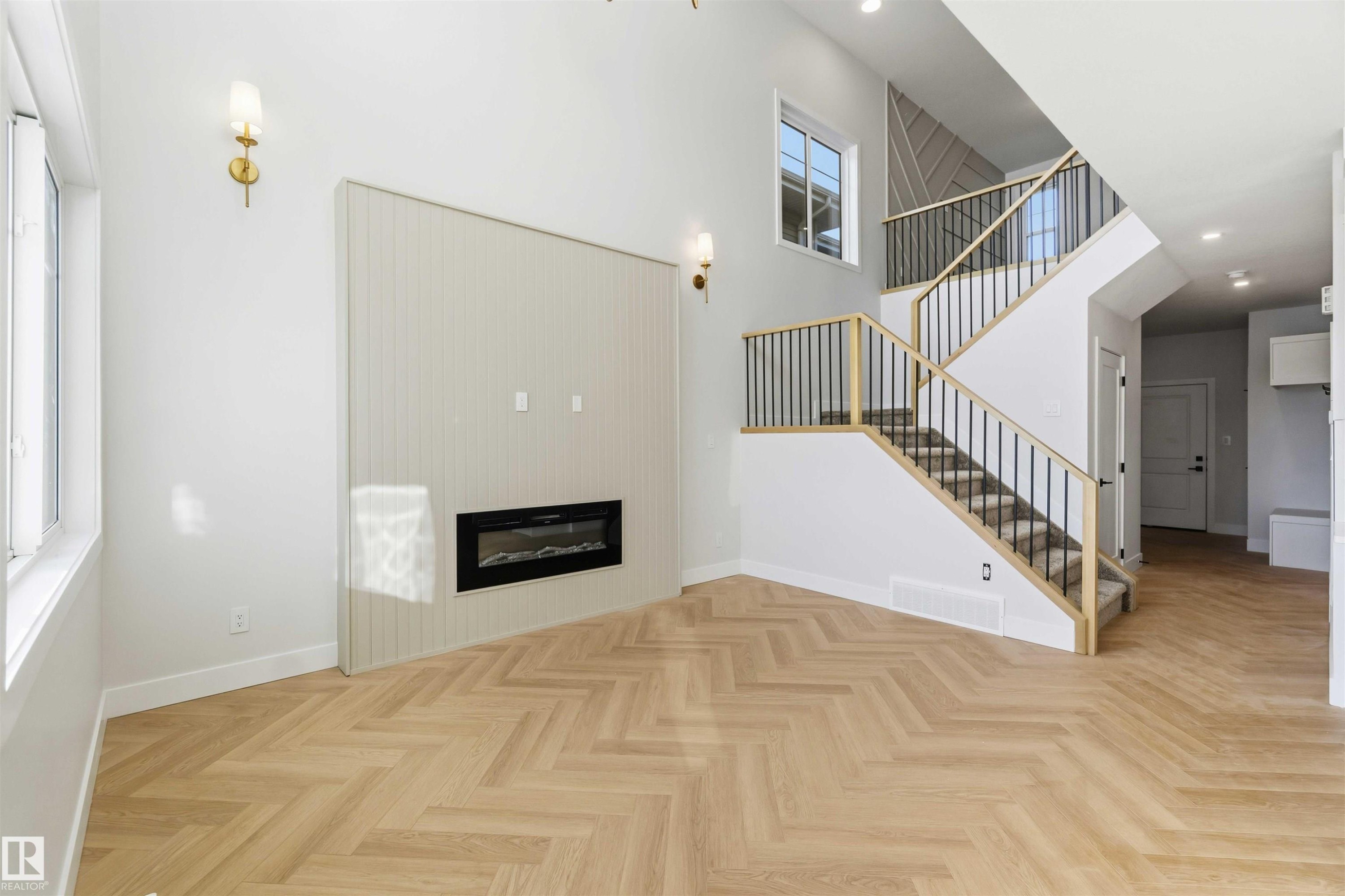 Unfurnished living room with a high ceiling, parquet floors, a glass covered fireplace, and recessed lighting - 94 Eldridge Pointe, St. Albert, AB - Indoor With Fireplace