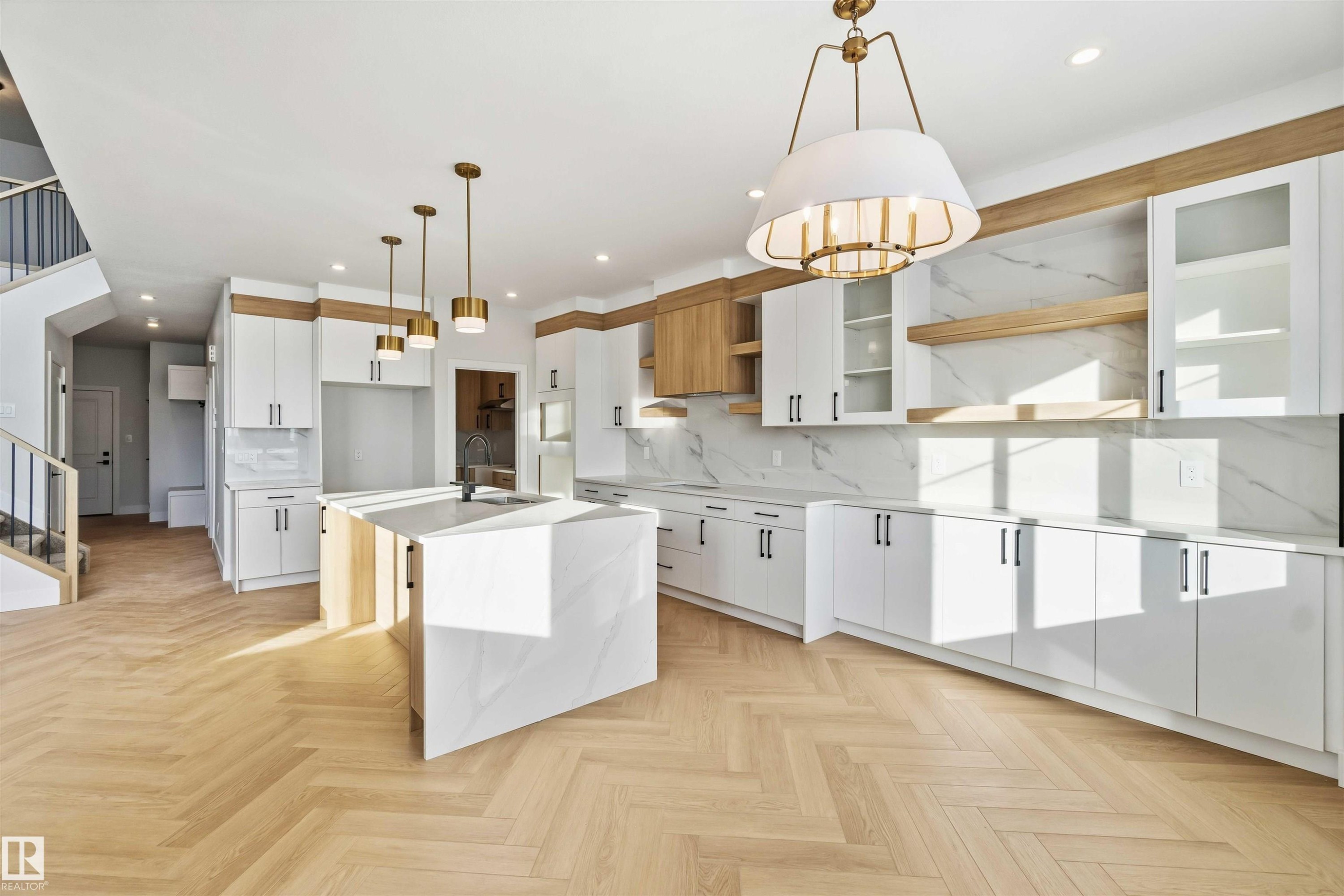 Kitchen featuring white cabinetry, an island with sink, parquet flooring, light stone counters, and decorative light fixtures - 94 Eldridge Pointe, St. Albert, AB - Indoor Photo Showing Kitchen With Upgraded Kitchen