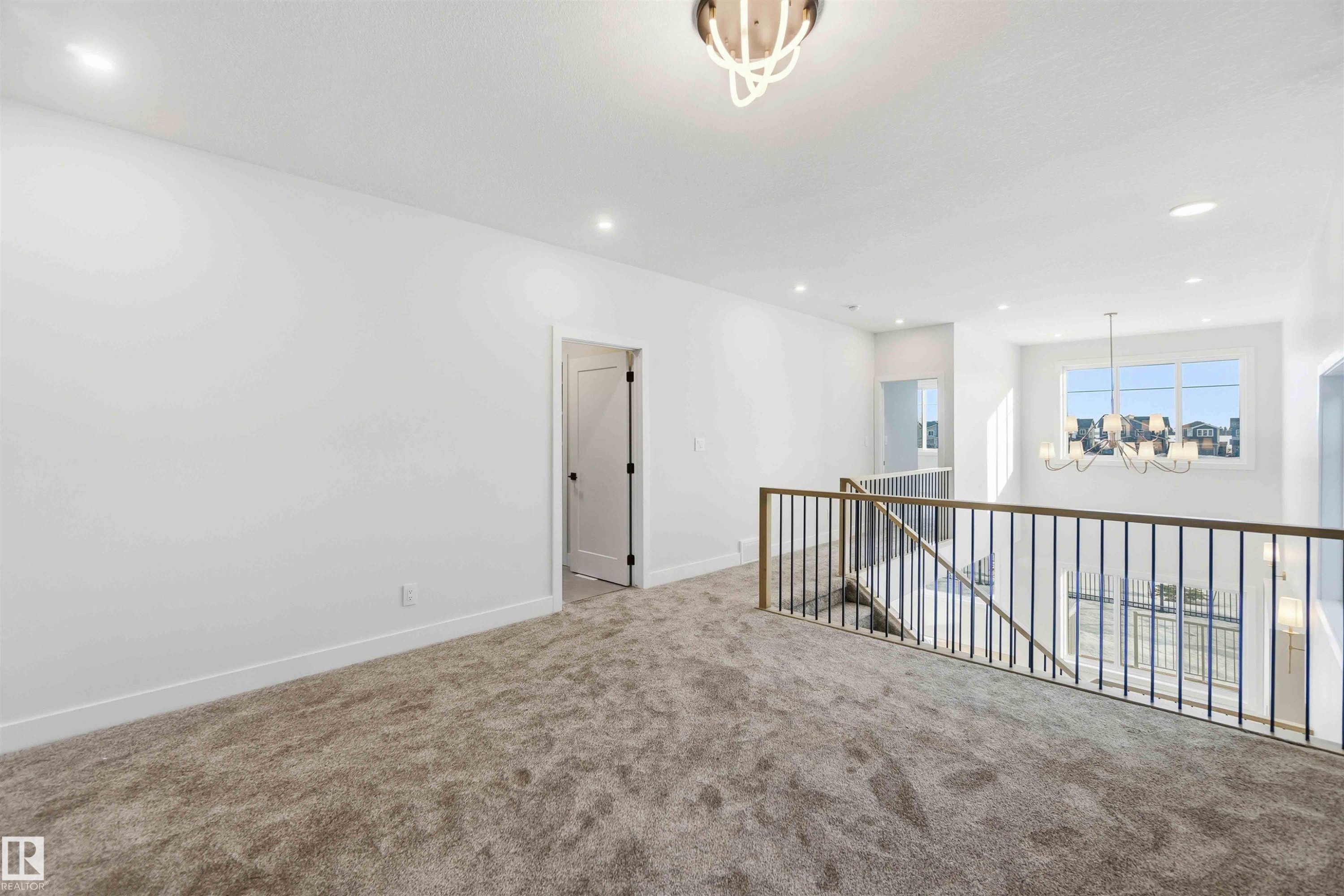 Carpeted spare room with hanging lights and baseboards - 94 Eldridge Pointe, St. Albert, AB - Indoor Photo Showing Other Room