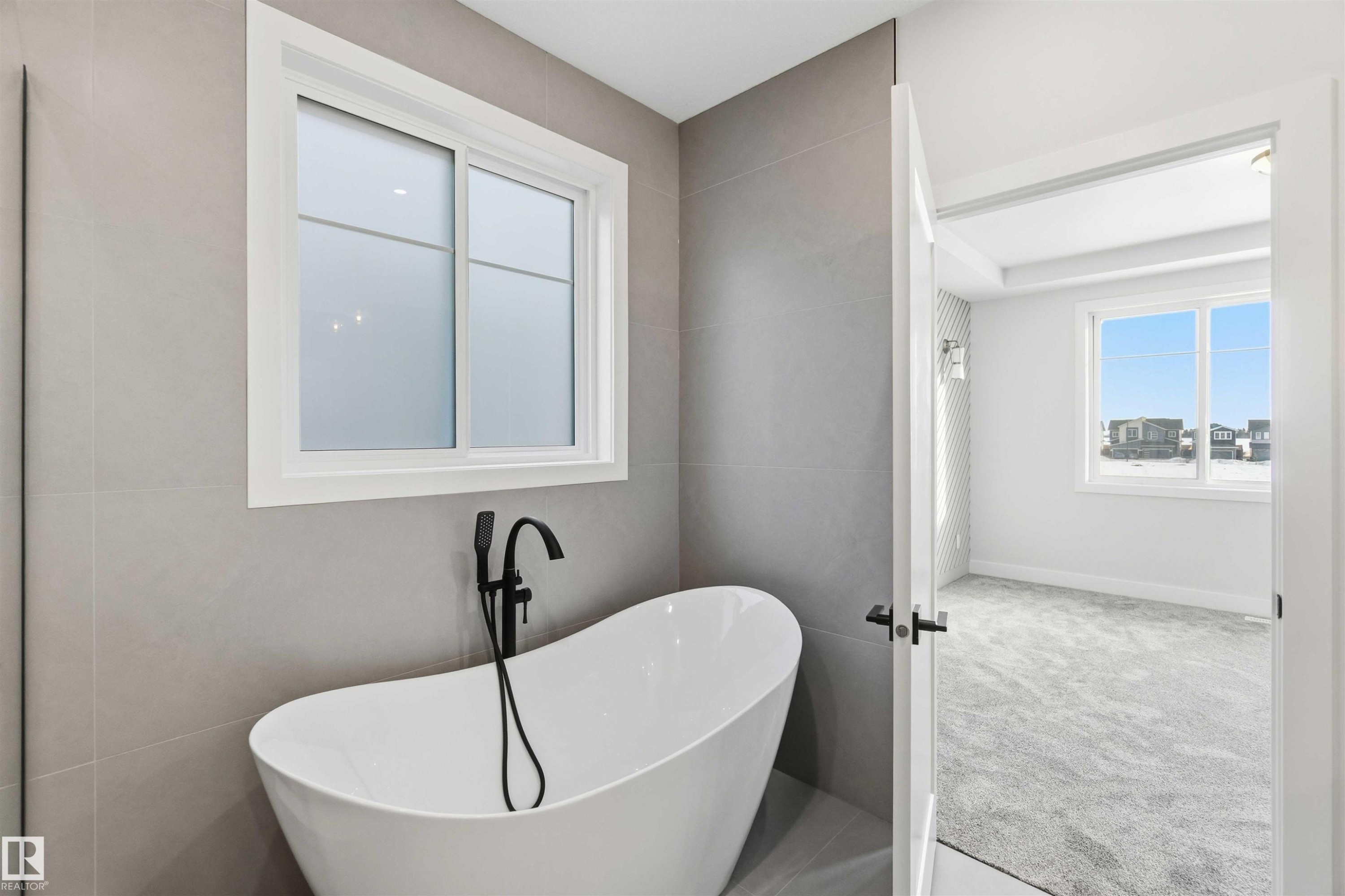 Bathroom with healthy amount of natural light, a soaking tub, tile walls, and carpet floors - 94 Eldridge Pointe, St. Albert, AB - Indoor Photo Showing Bathroom