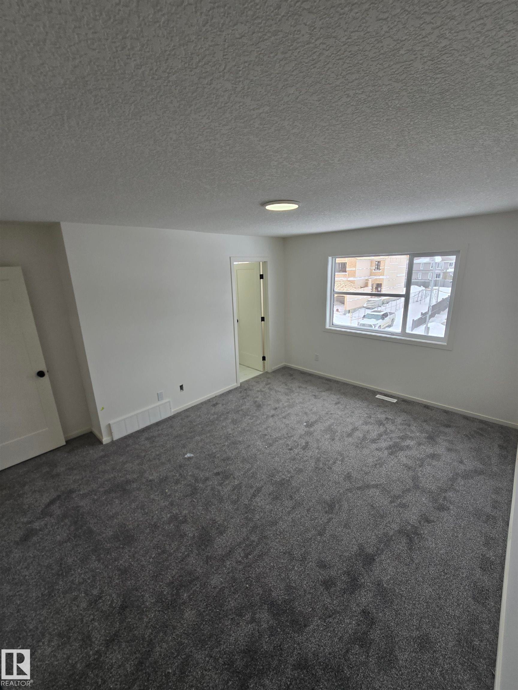 Unfurnished room with dark colored carpet and a textured ceiling - 7706 174A Avenue, Edmonton, AB - Indoor Photo Showing Other Room