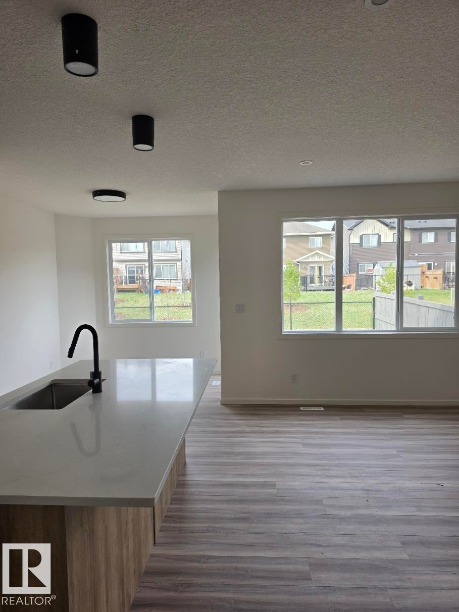 Kitchen island featuring a light-toned countertop with an undermount sink and matte black gooseneck faucet - 7706 174A Avenue, Edmonton, AB - Indoor