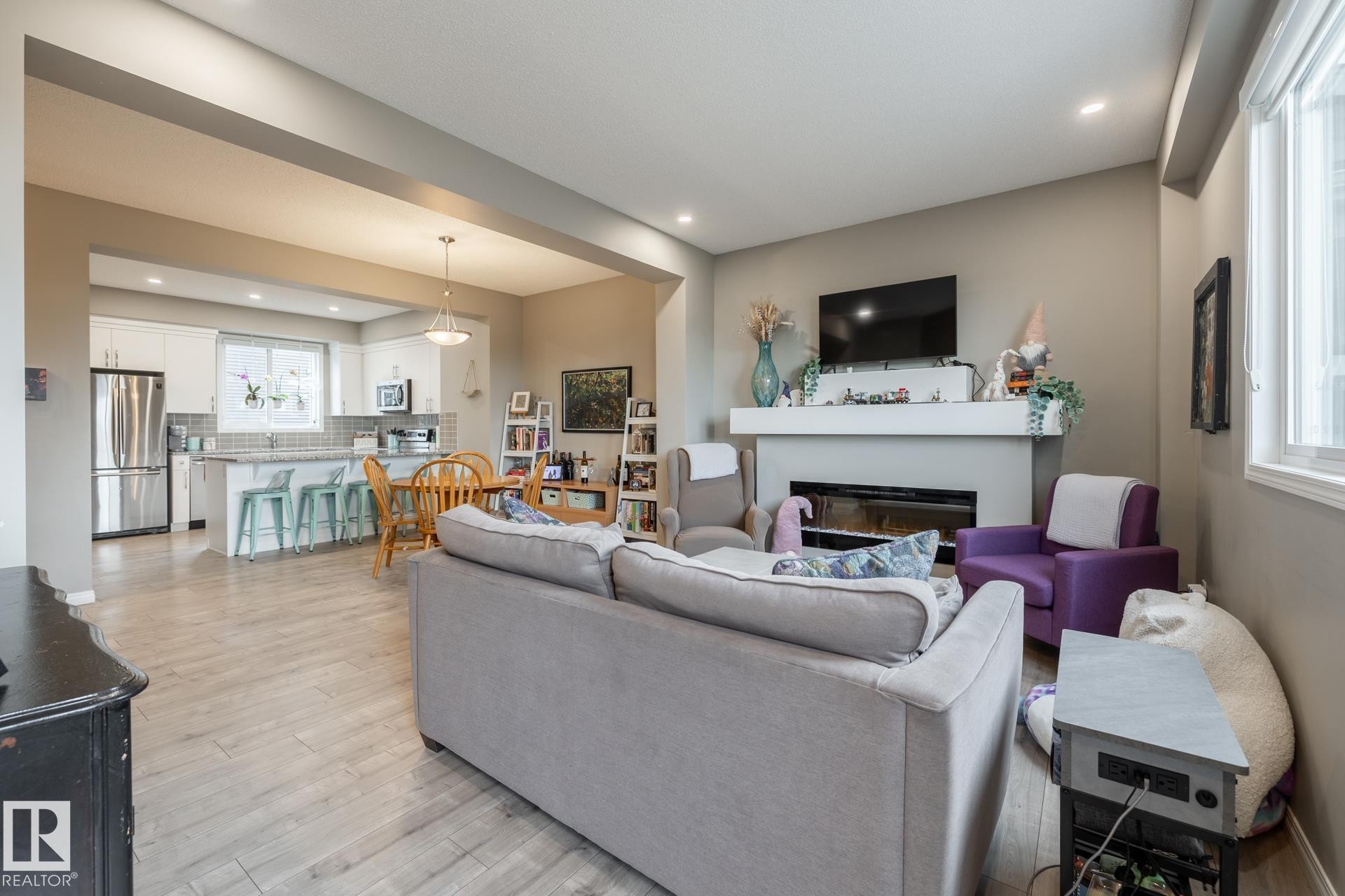 Living room featuring light wood-style flooring, a glass covered fireplace, and recessed lighting - 5 2072 Wonnacott Way, Edmonton, AB - Indoor Photo Showing Living Room With Fireplace