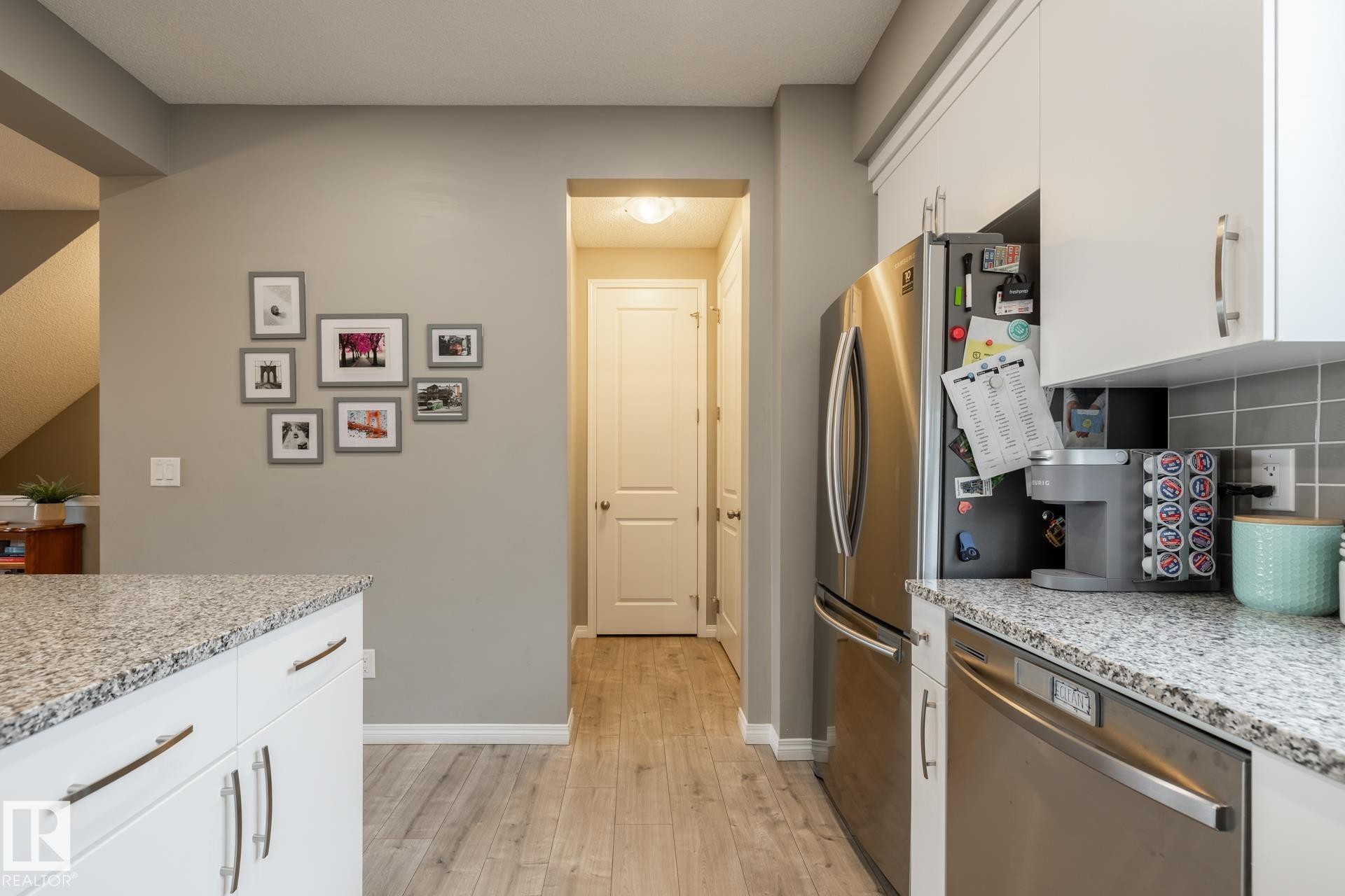 Kitchen featuring white cabinetry, dishwasher, and light stone countertops - 5 2072 Wonnacott Way, Edmonton, AB - Indoor Photo Showing Kitchen