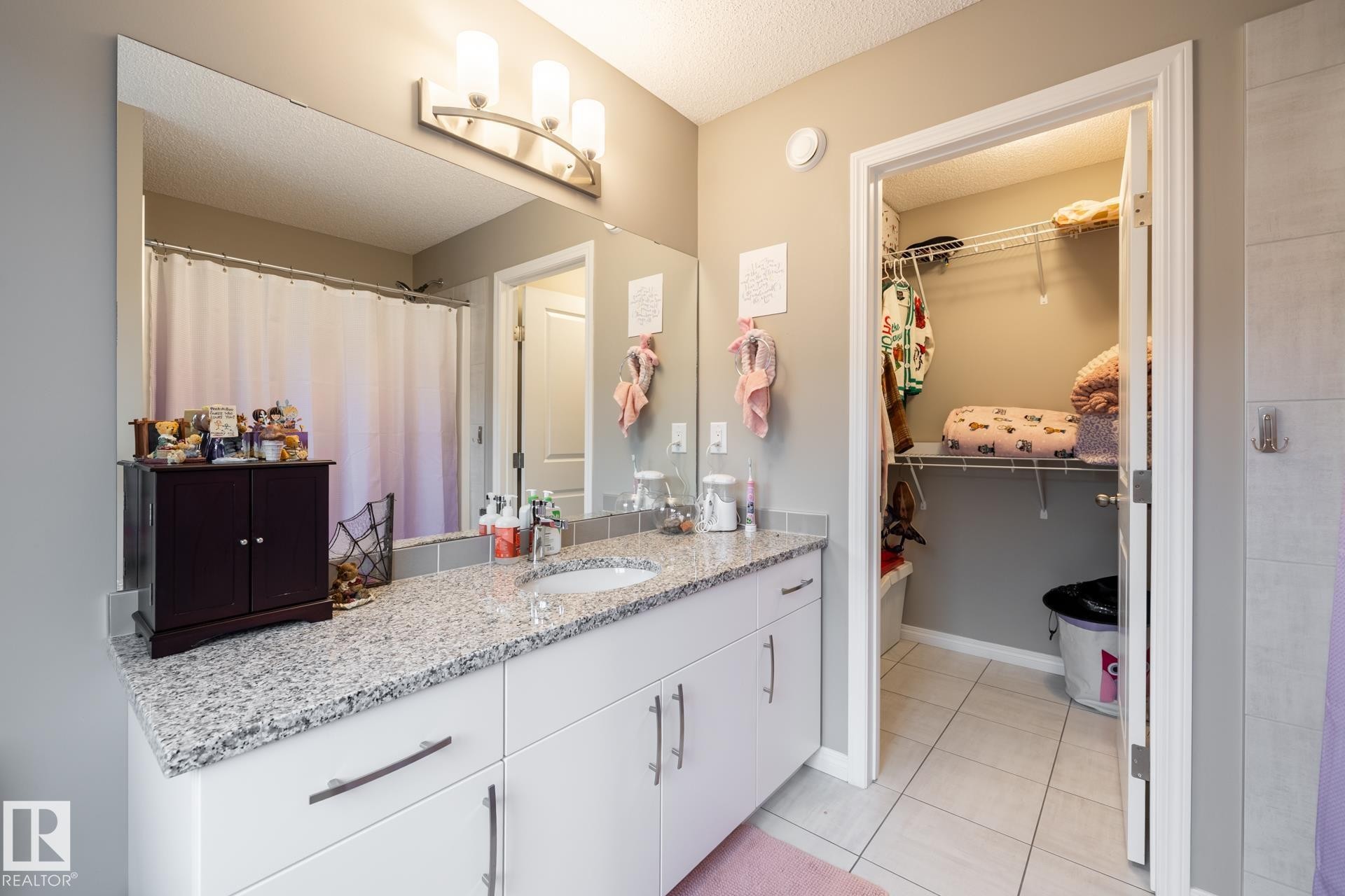 Bathroom featuring vanity, curtained shower, a textured ceiling, light tile patterned floors, and a walk in closet - 5 2072 Wonnacott Way, Edmonton, AB - Indoor Photo Showing Bathroom