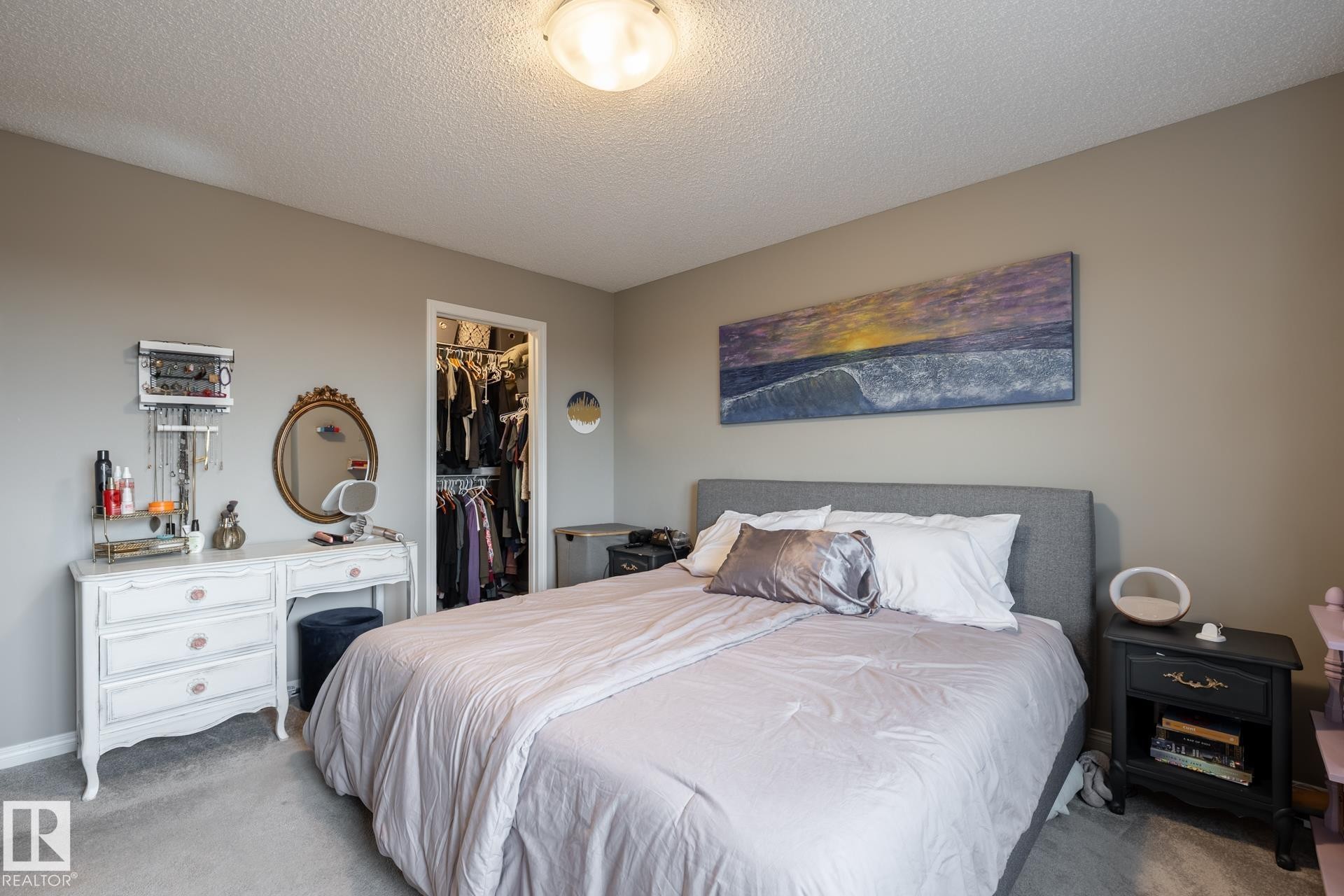 Bedroom with light colored carpet, a textured ceiling, and a walk in closet - 5 2072 Wonnacott Way, Edmonton, AB - Indoor Photo Showing Bedroom
