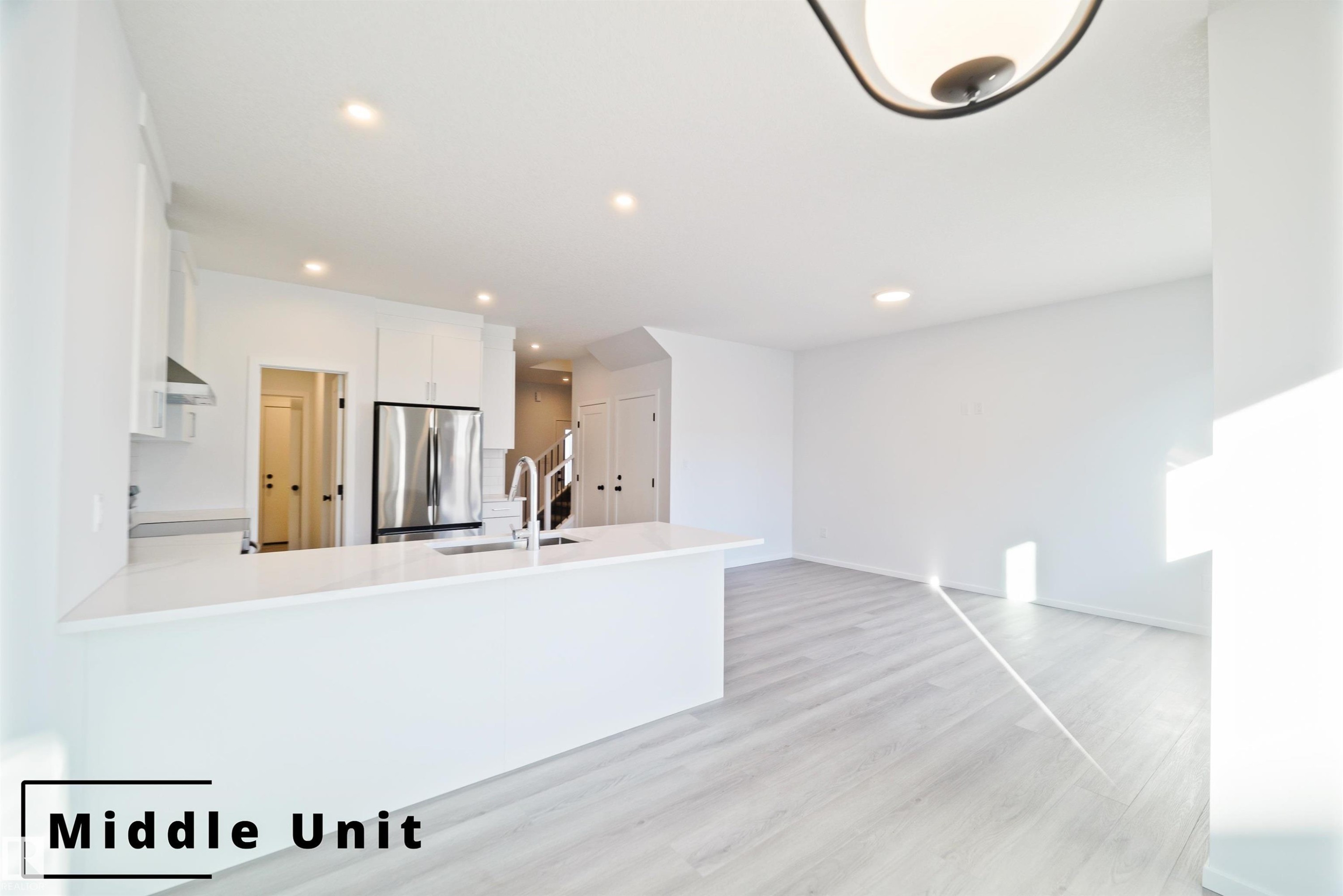Kitchen with white cabinets, freestanding refrigerator, light wood-style flooring, a peninsula, and recessed lighting - 7585 174A Avenue, Edmonton, AB - Indoor Photo Showing Other Room