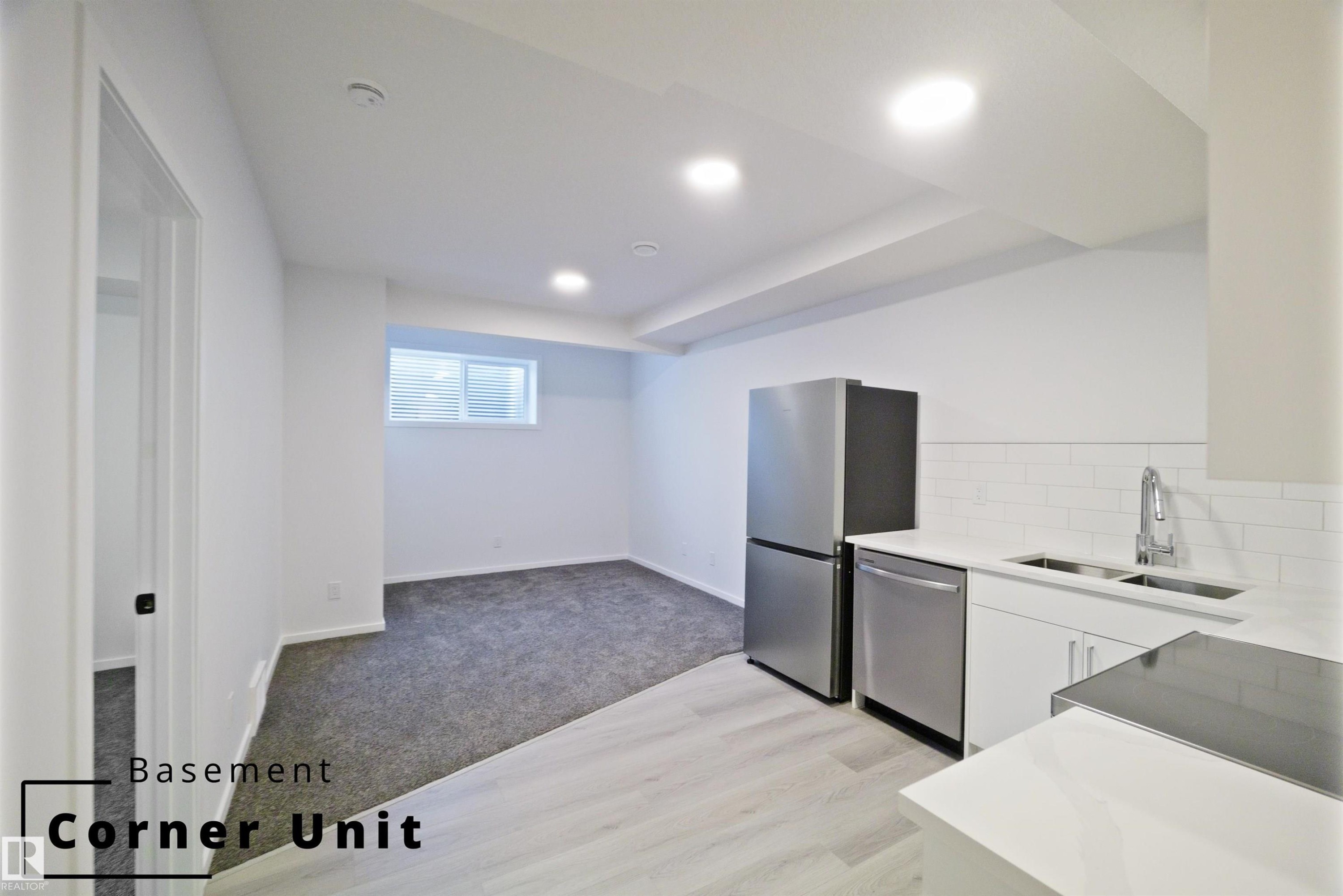 Kitchen featuring decorative backsplash, light colored carpet, stainless steel dishwasher, electric range, and light stone countertops - 7585 174A Avenue, Edmonton, AB - Indoor