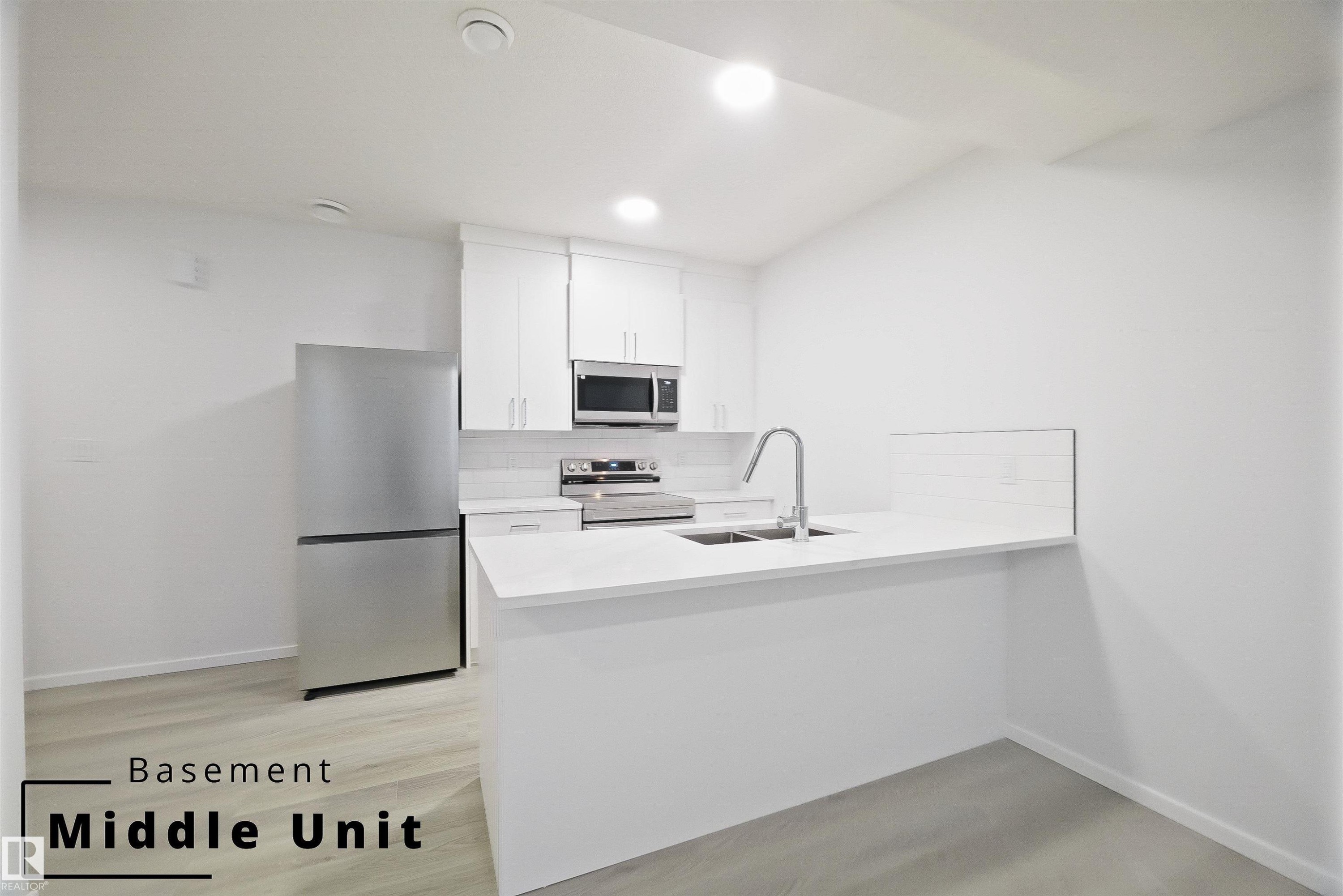 Kitchen with stainless steel appliances, backsplash, white cabinetry, a peninsula, and light stone countertops - 7585 174A Avenue, Edmonton, AB - Indoor Photo Showing Kitchen