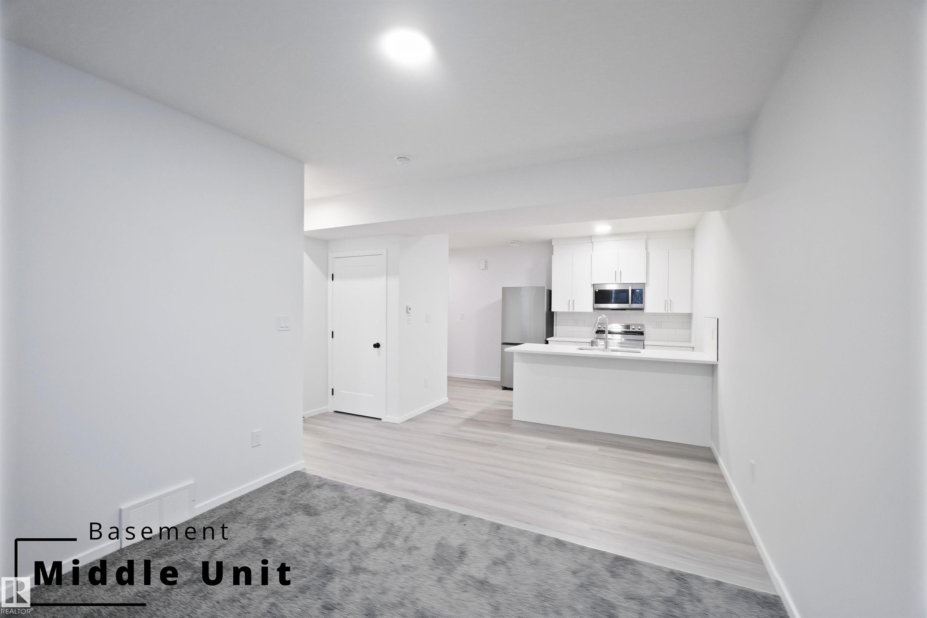 Unfurnished living room with light carpet, recessed lighting, and light wood finished floors - 7585 174A Avenue, Edmonton, AB - Indoor Photo Showing Kitchen