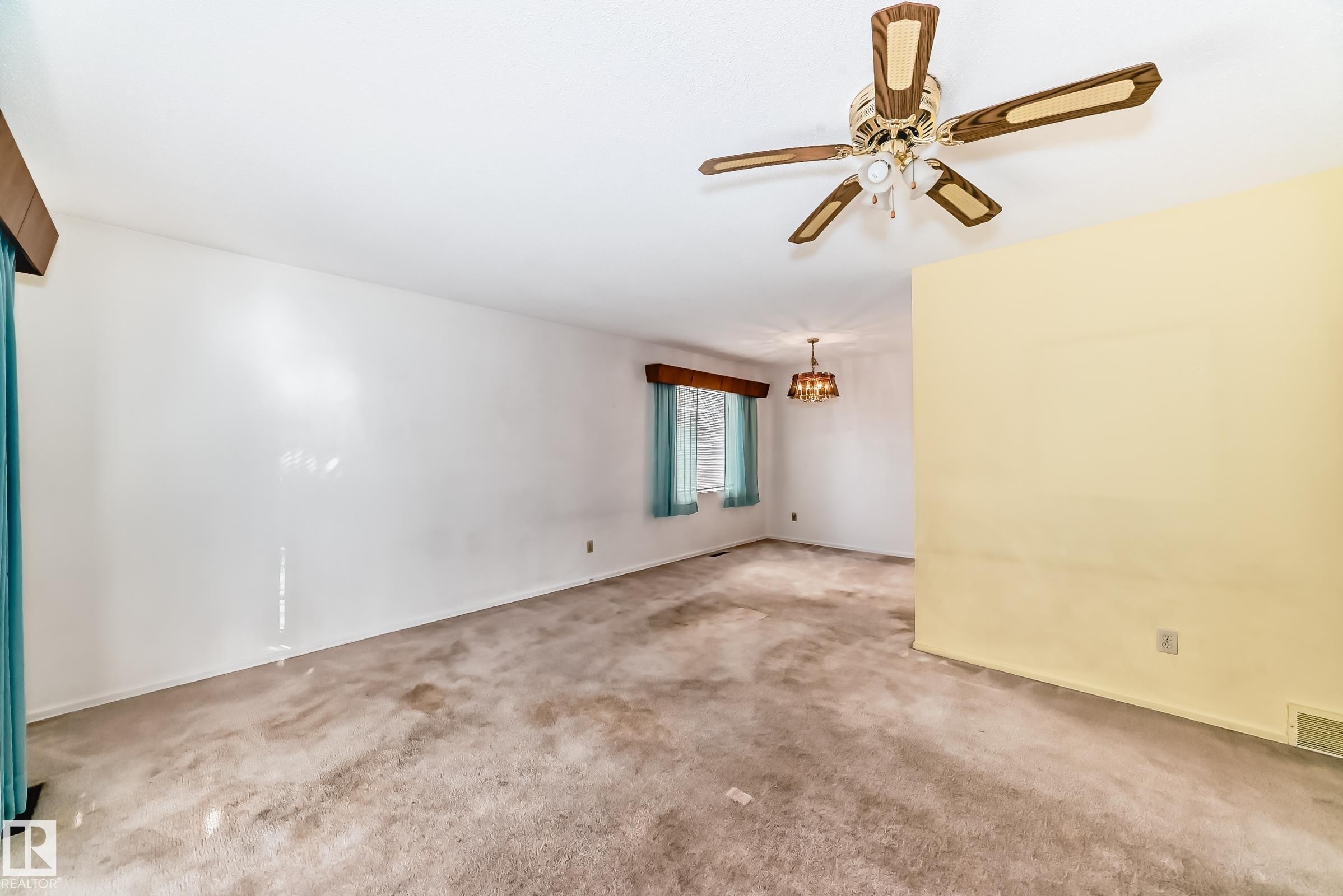 Carpeted spare room with a ceiling fan and a chandelier - Edmonton, AB - Indoor Photo Showing Other Room