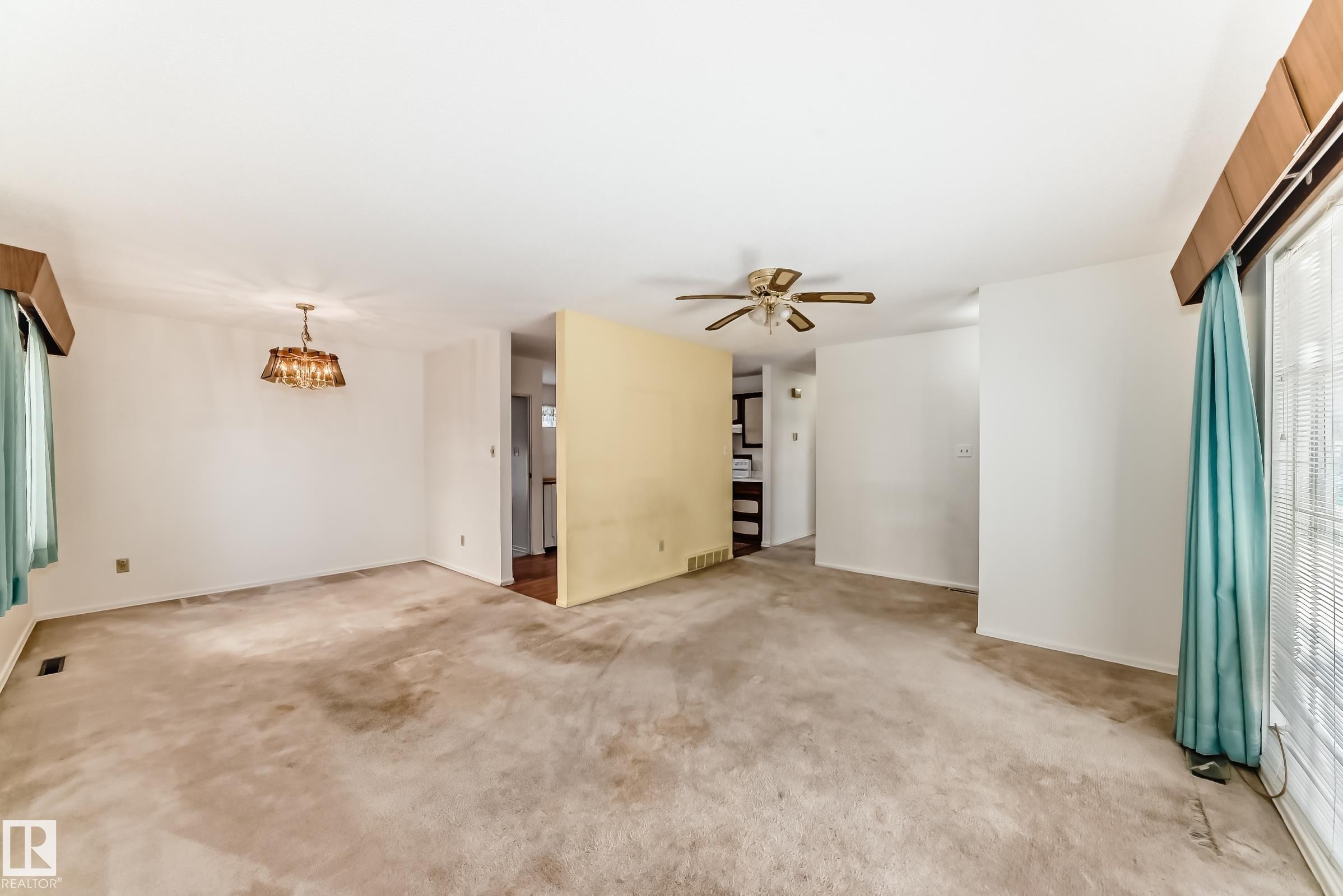 Unfurnished living room with carpet flooring, a ceiling fan, and a chandelier - Edmonton, AB - Indoor