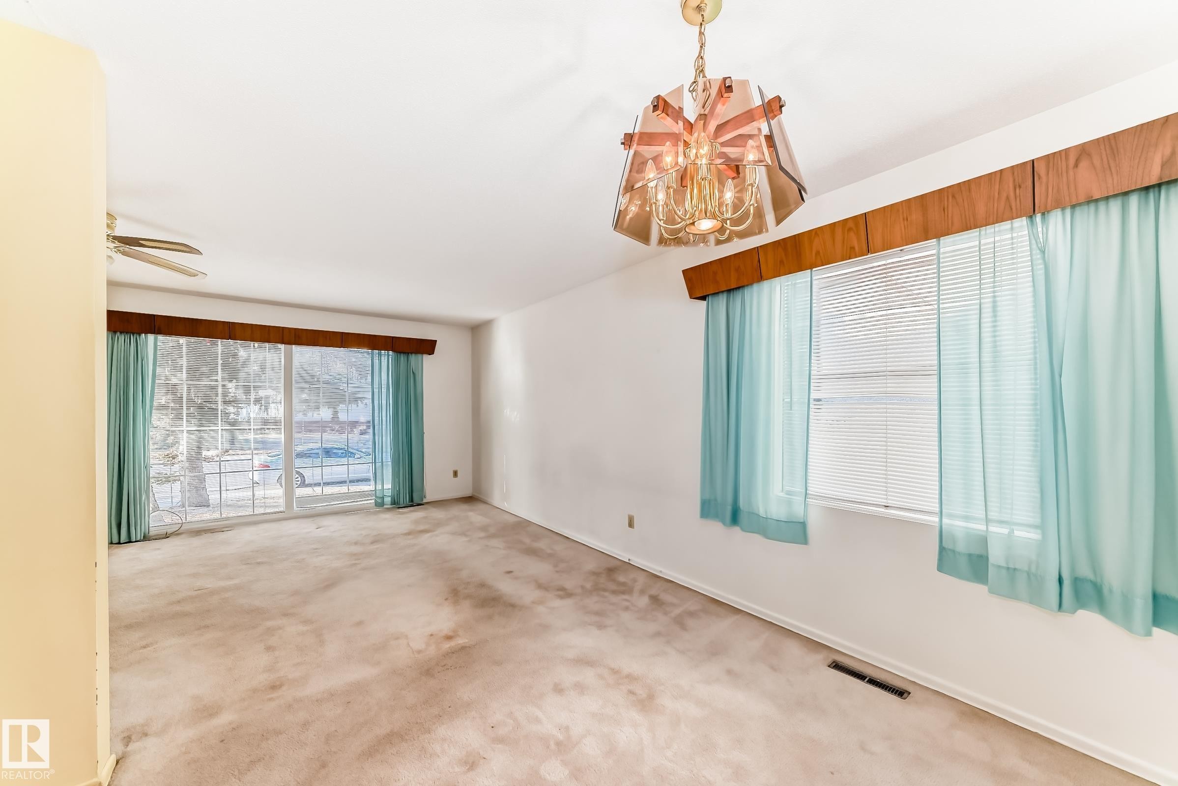 Carpeted spare room with a chandelier and a ceiling fan - Edmonton, AB - Indoor Photo Showing Other Room