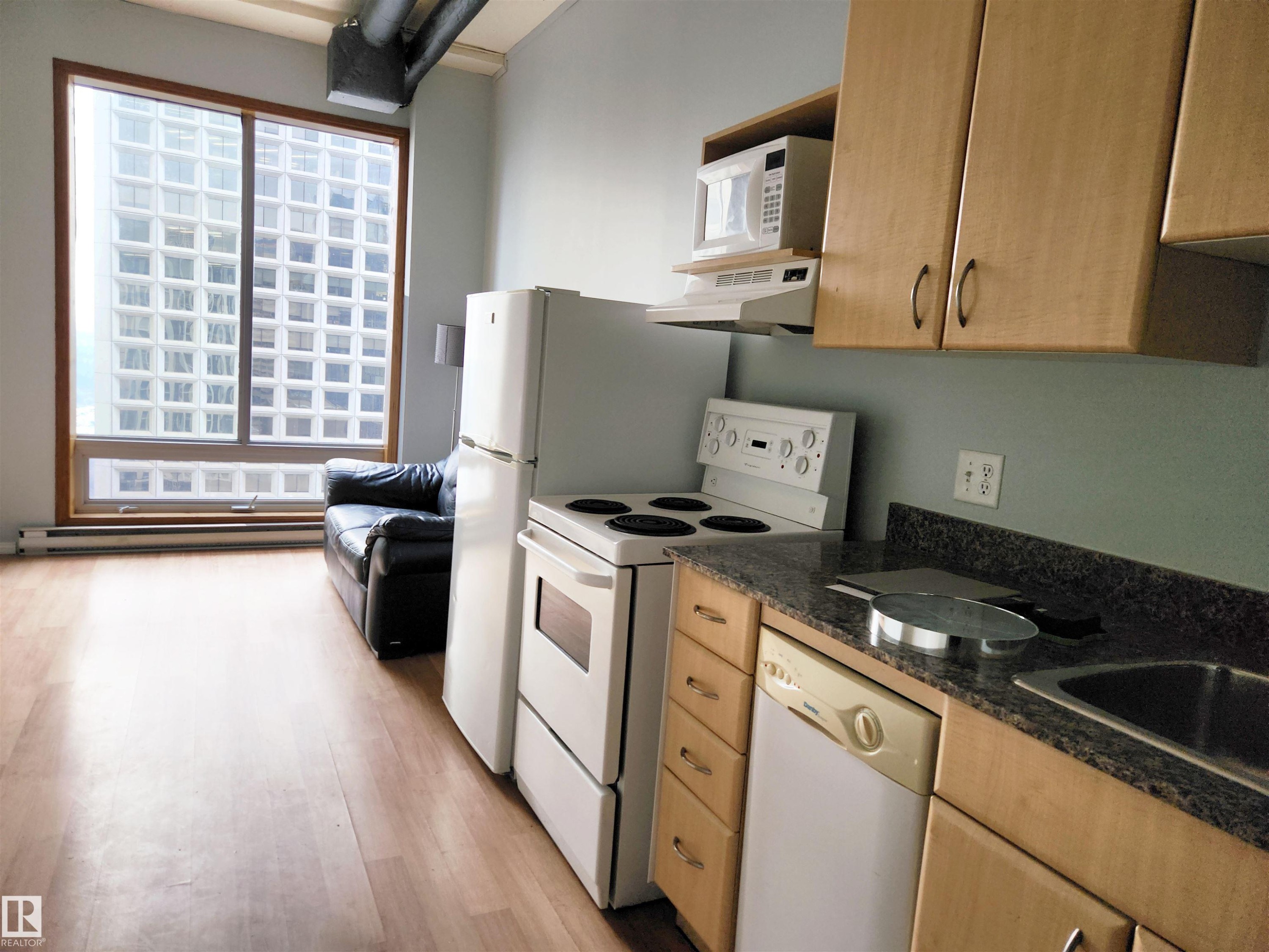 Kitchen with white appliances, under cabinet range hood, light wood-style flooring, a baseboard radiator, and light brown cabinets - 1410 10024 Jasper Avenue, Edmonton, AB - Indoor Photo Showing Kitchen