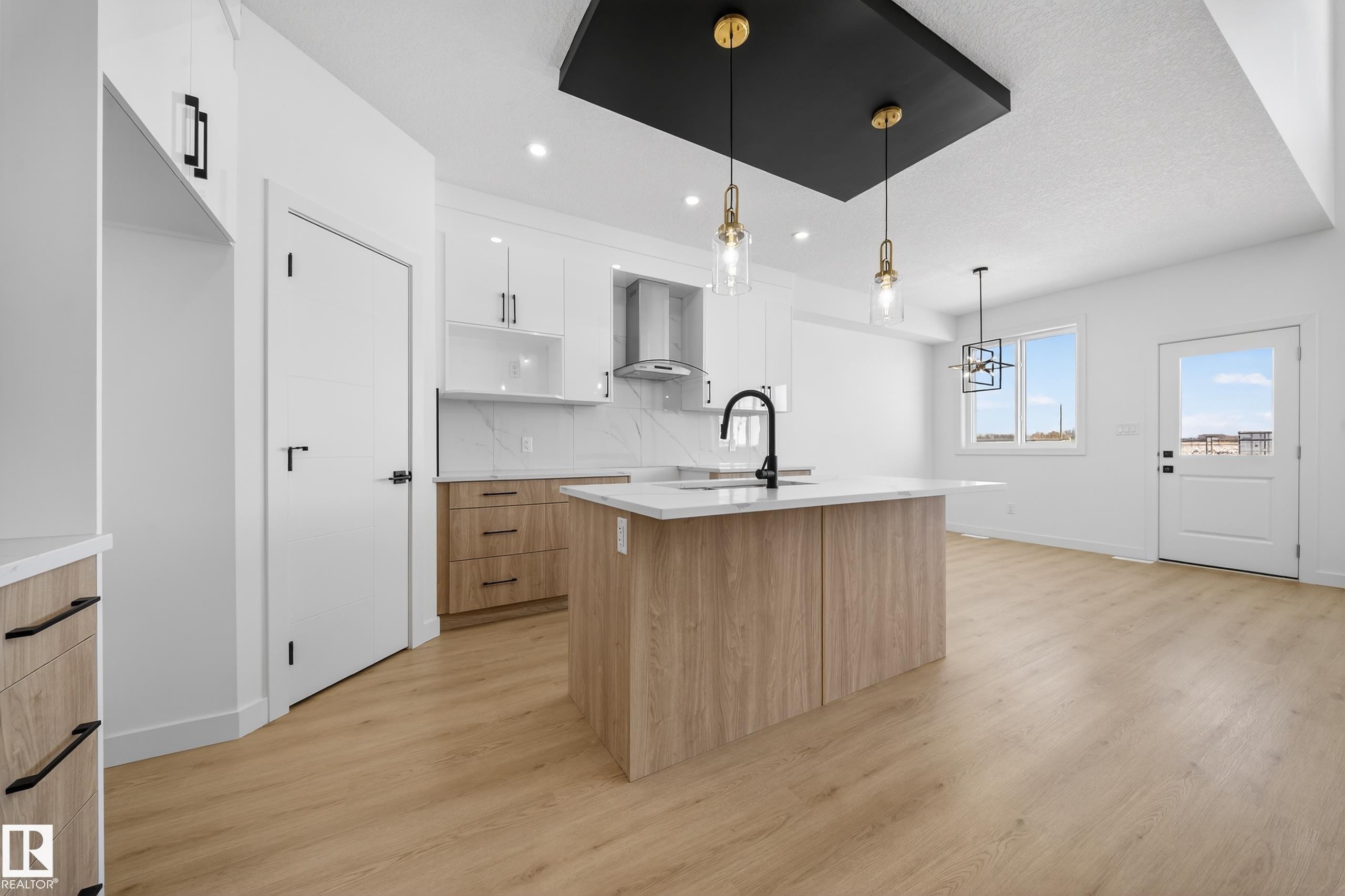 Kitchen featuring dual tone cabinetry, modern cabinets, an island with sink, light wood-style flooring, and pendant lighting - 129 Pierwyck Loop, Spruce Grove, AB - Indoor Photo Showing Kitchen With Upgraded Kitchen
