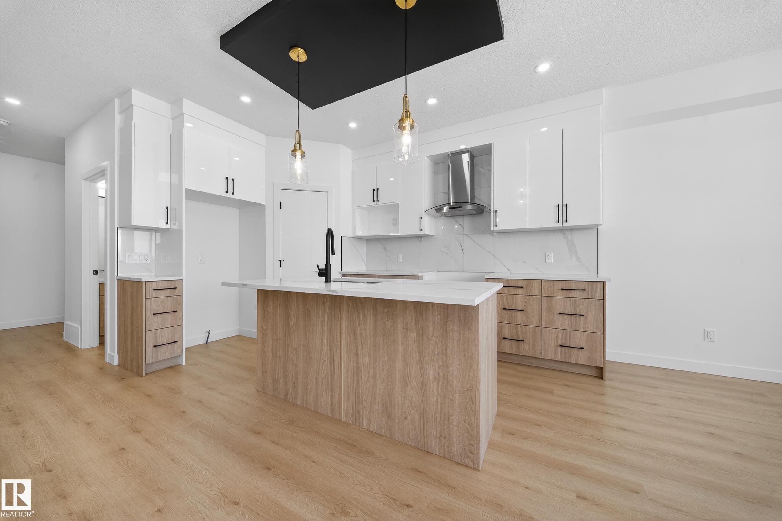 Kitchen with dual tone cabinets, an island with sink, modern cabinets, light wood-style floors, and pendant lighting - 129 Pierwyck Loop, Spruce Grove, AB - Indoor Photo Showing Kitchen With Upgraded Kitchen